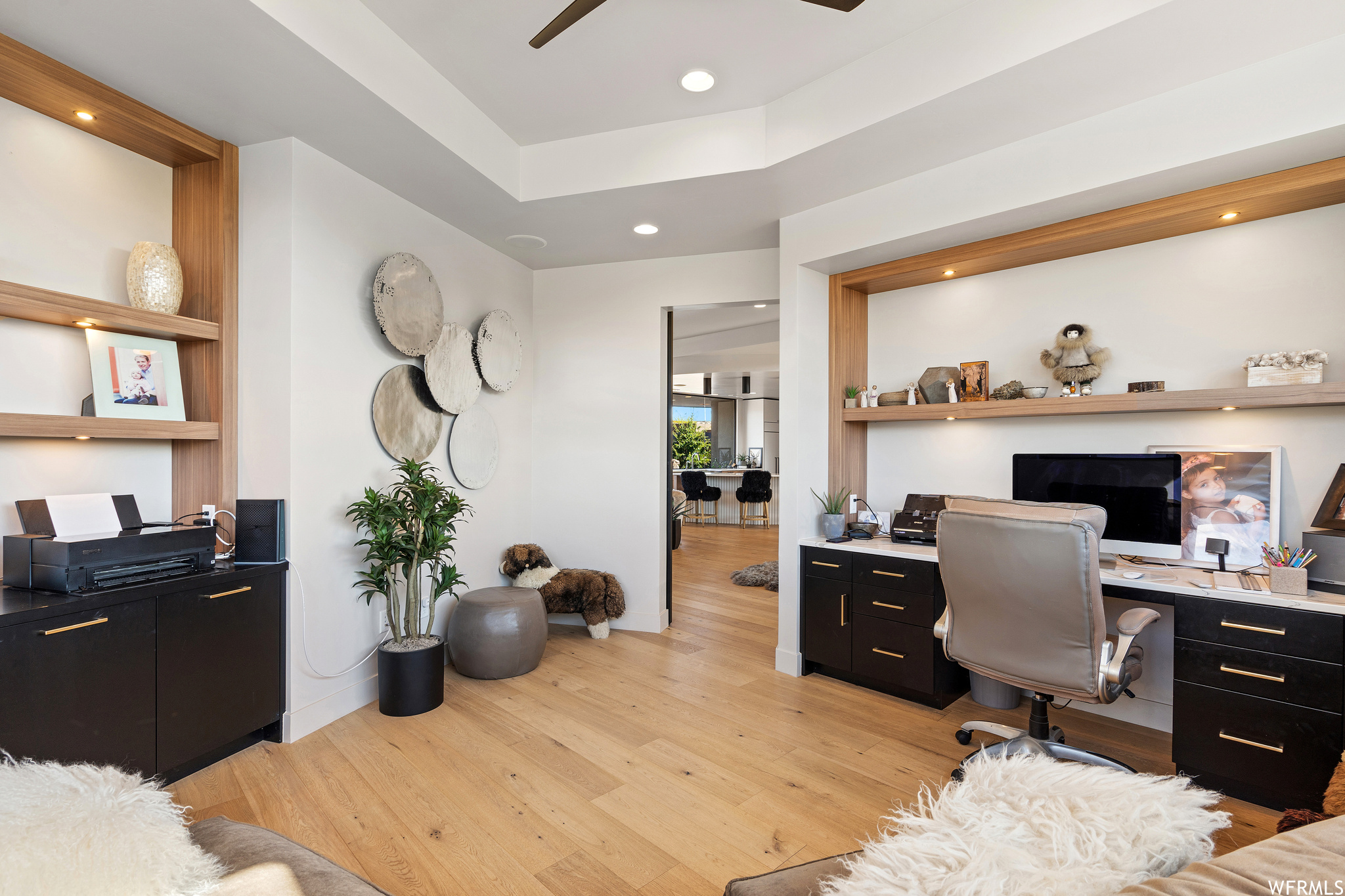 Office with built in desk, ceiling fan, and light hardwood / wood-style floors