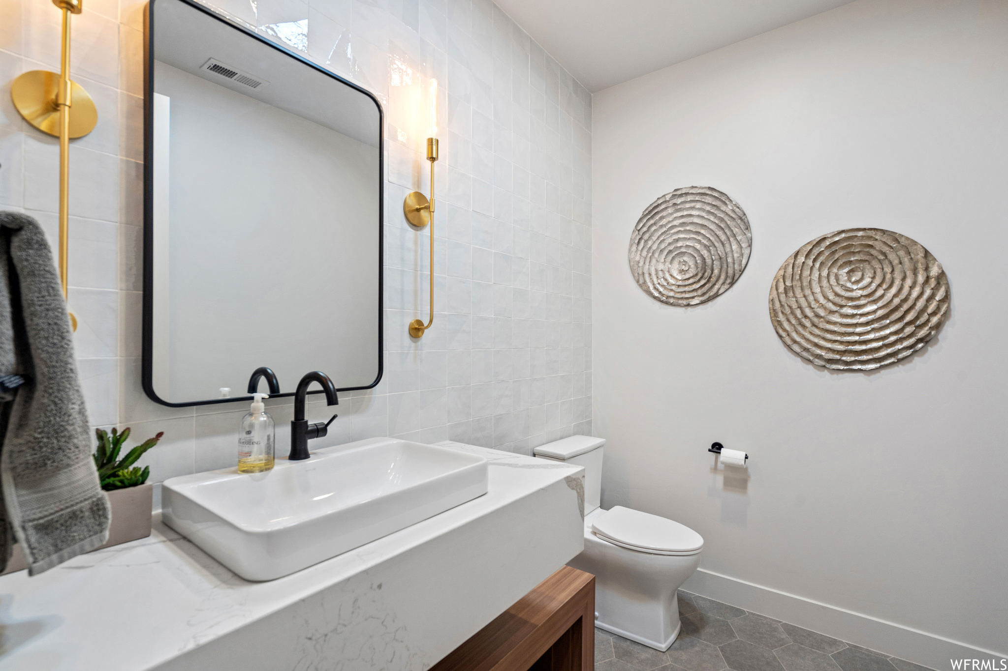 Bathroom featuring toilet, tile floors, tile walls, and vanity