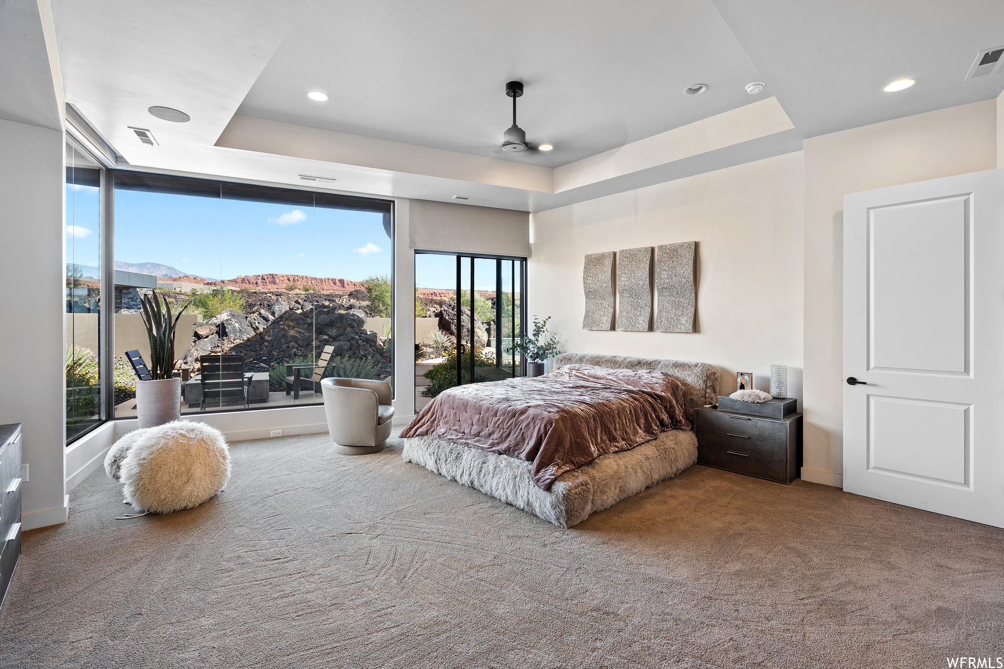 Bedroom with light carpet, a raised ceiling, ceiling fan, and access to exterior
