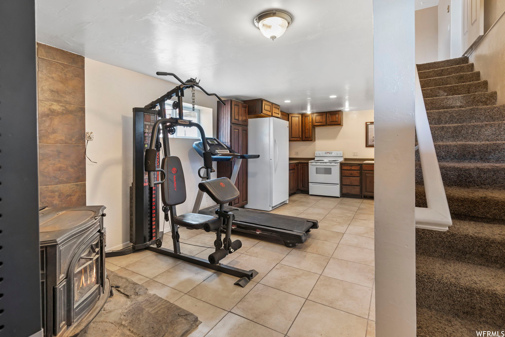 Workout area featuring a wood stove and light tile floors