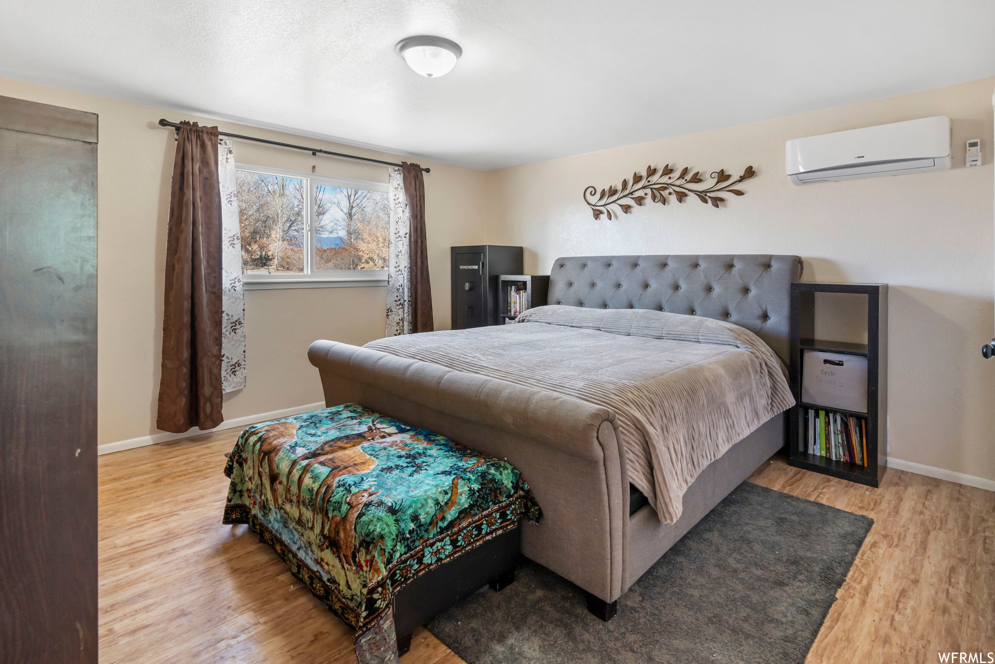 Bedroom with a wall unit AC and light hardwood / wood-style floors