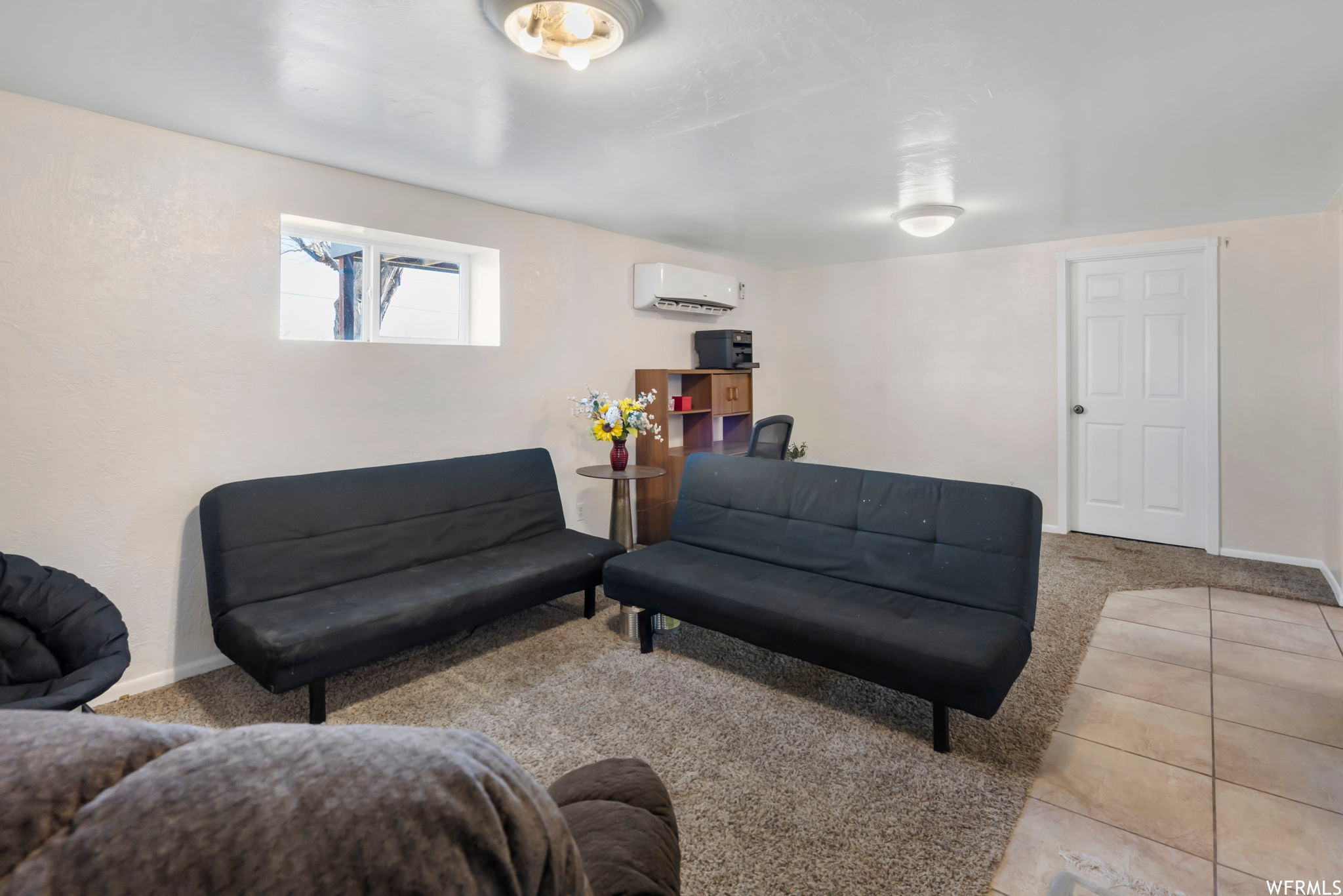 Living room featuring light tile floors and a wall unit AC