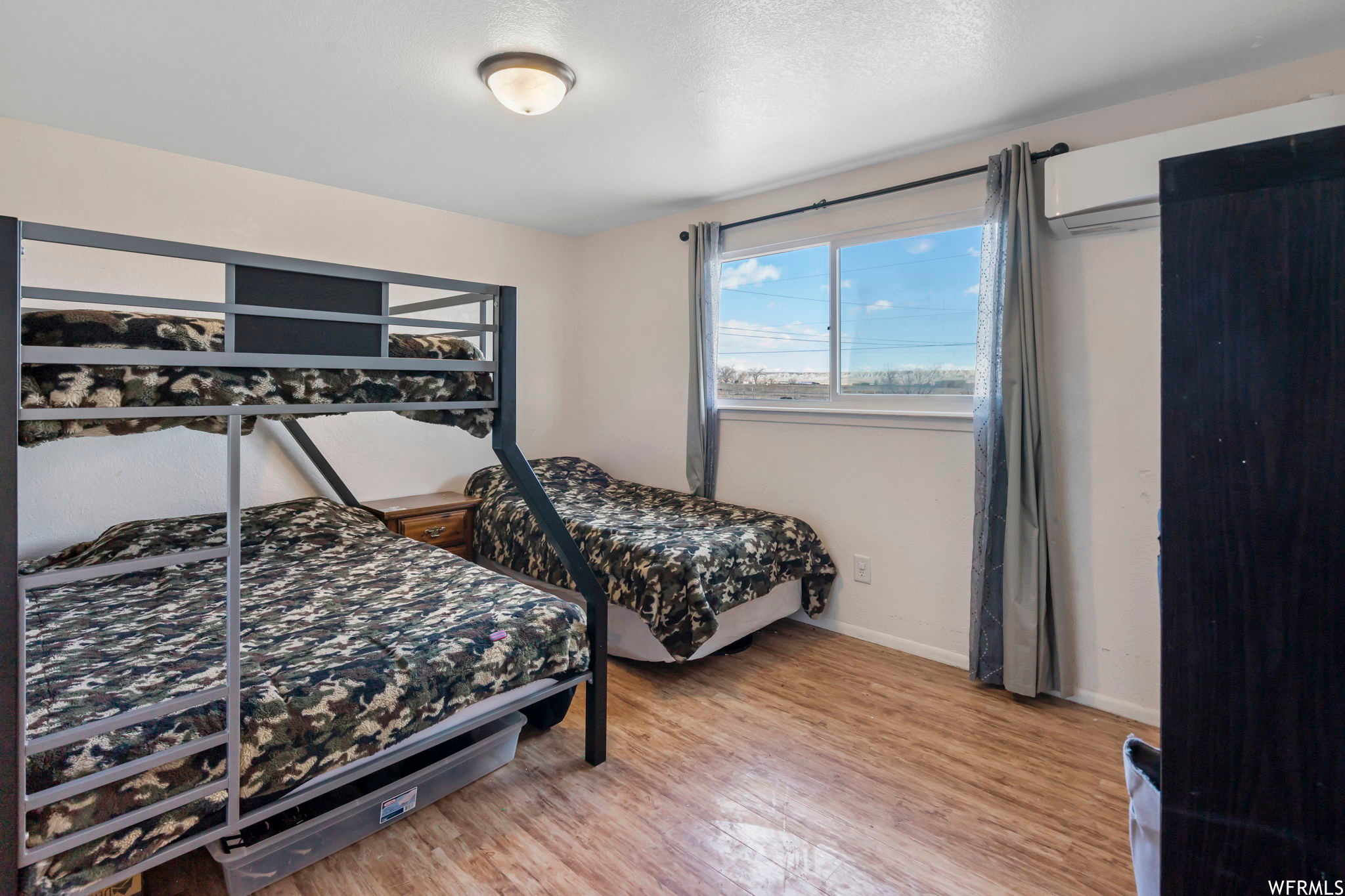 Bedroom with an AC wall unit and light hardwood / wood-style floors