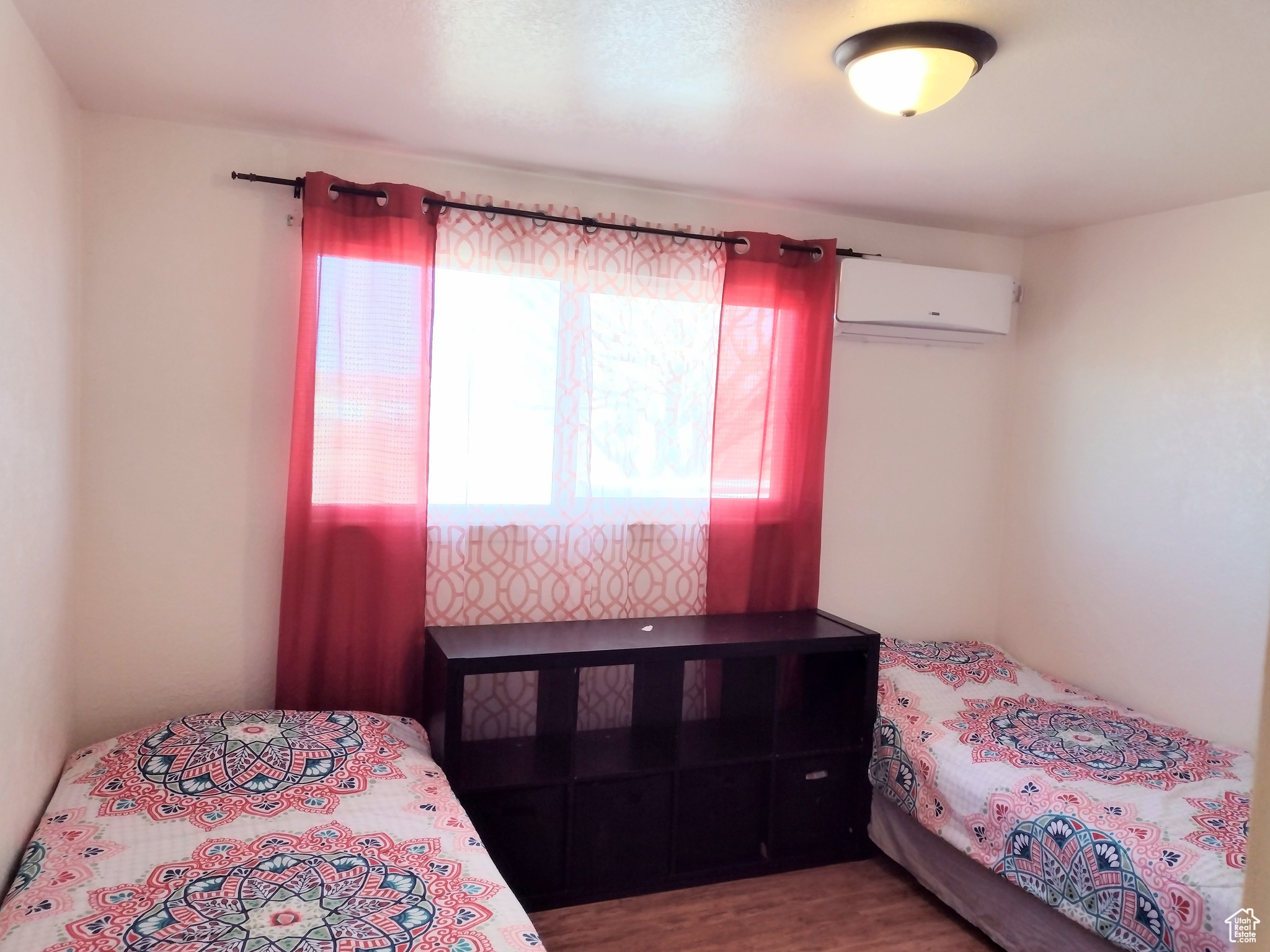 Bedroom with a wall unit AC and dark wood-type flooring