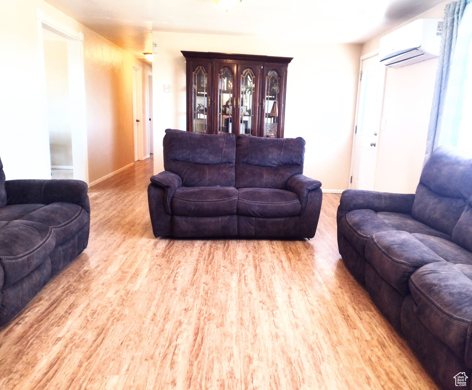 Living room featuring light wood-type flooring and an AC wall unit