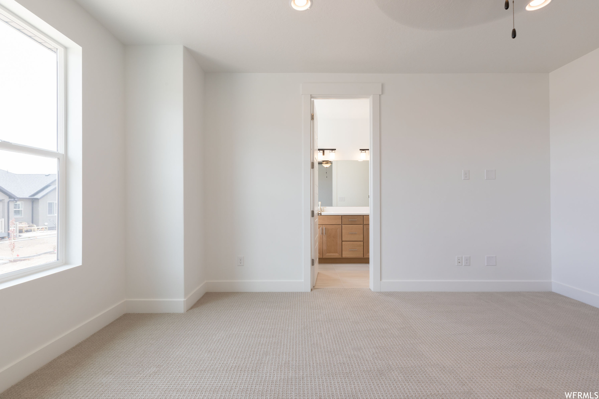 Interior space featuring ensuite bathroom and light carpet