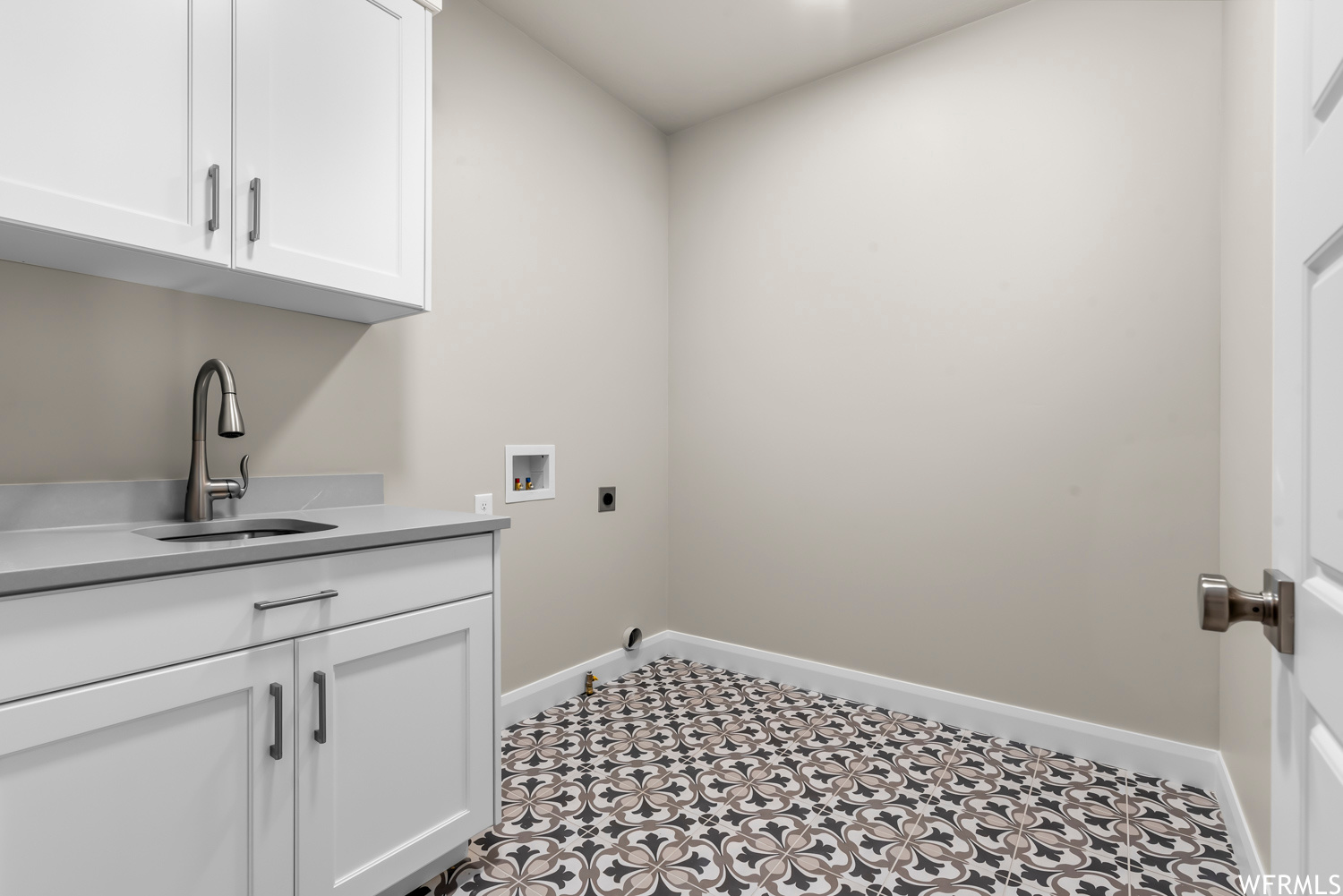 Washroom featuring cabinets, light tile flooring, sink, and hookup for a washing machine