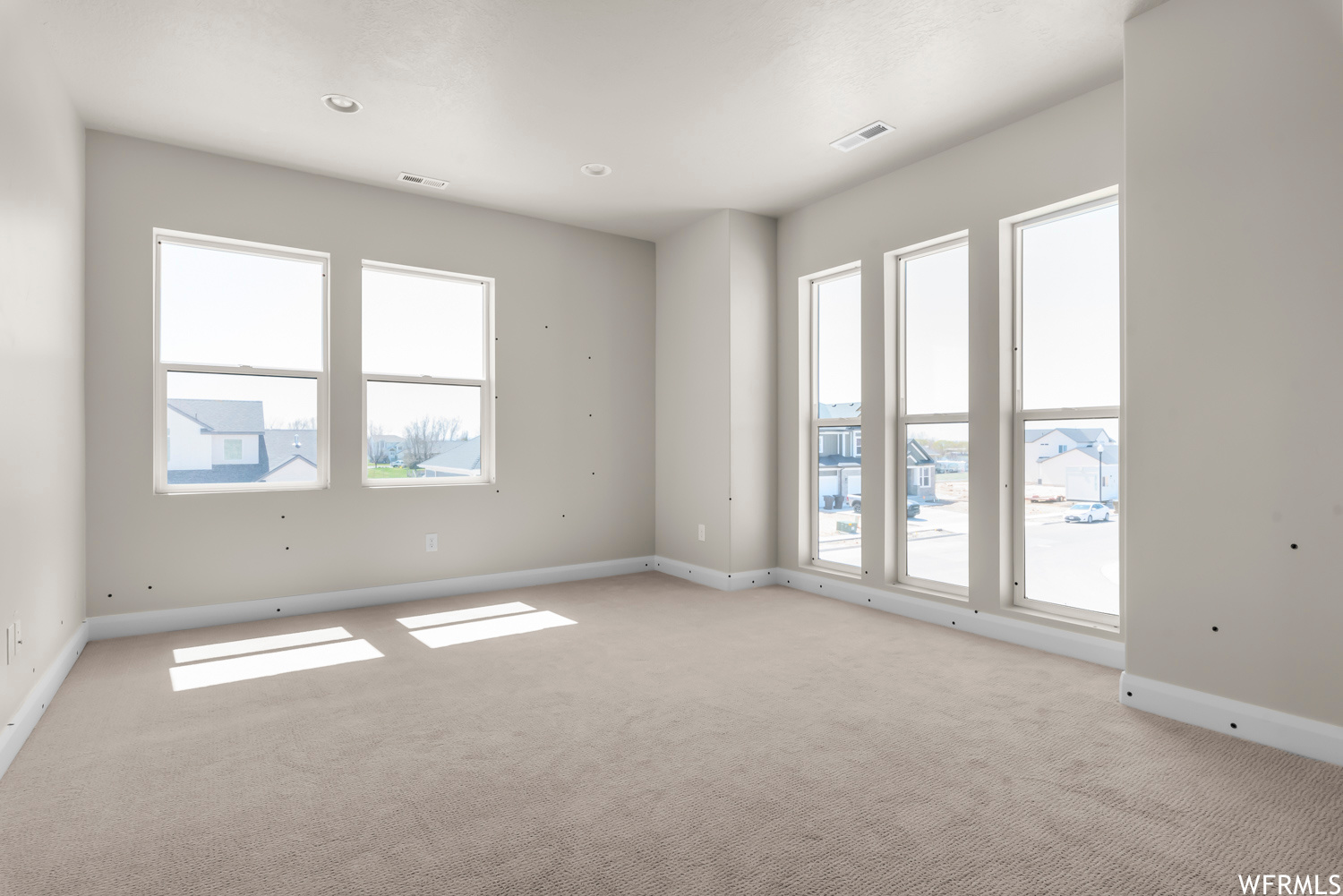Unfurnished room with a wealth of natural light and light carpet