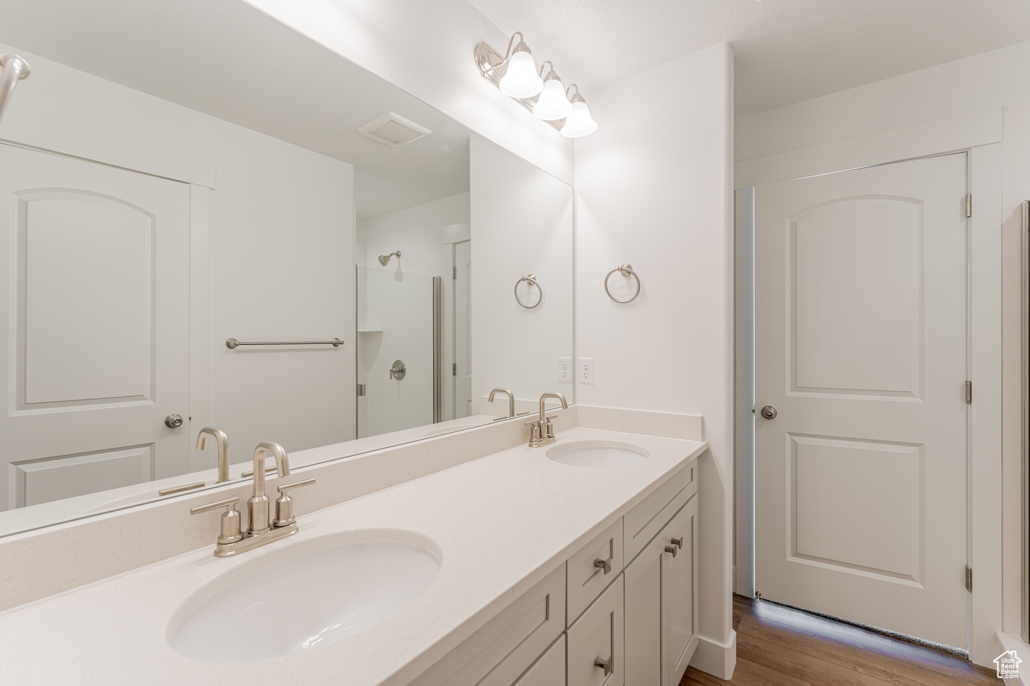 Bathroom with wood-type flooring, oversized vanity, and double sink