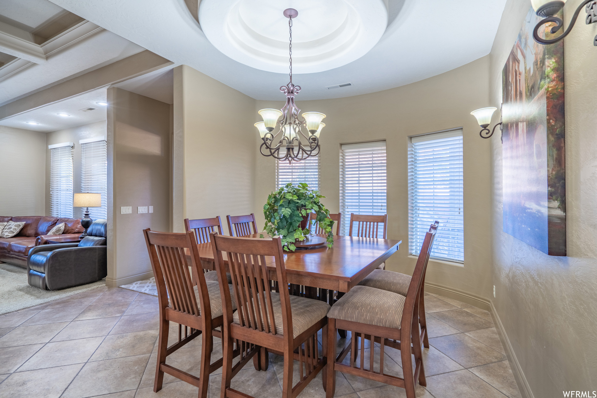 Dining space with light tile floors, an inviting chandelier, and a raised ceiling