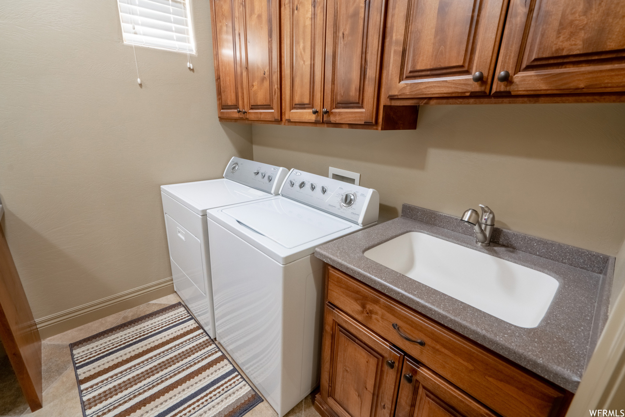 Washroom with washer hookup, light tile flooring, cabinets, sink, and washing machine and clothes dryer