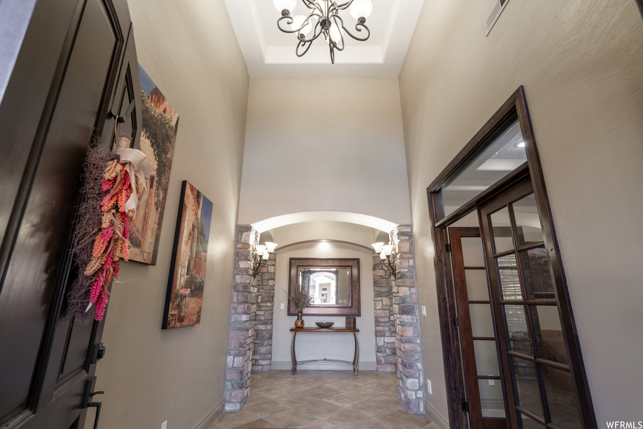 Tiled entrance foyer featuring a chandelier, a raised ceiling, and a towering ceiling