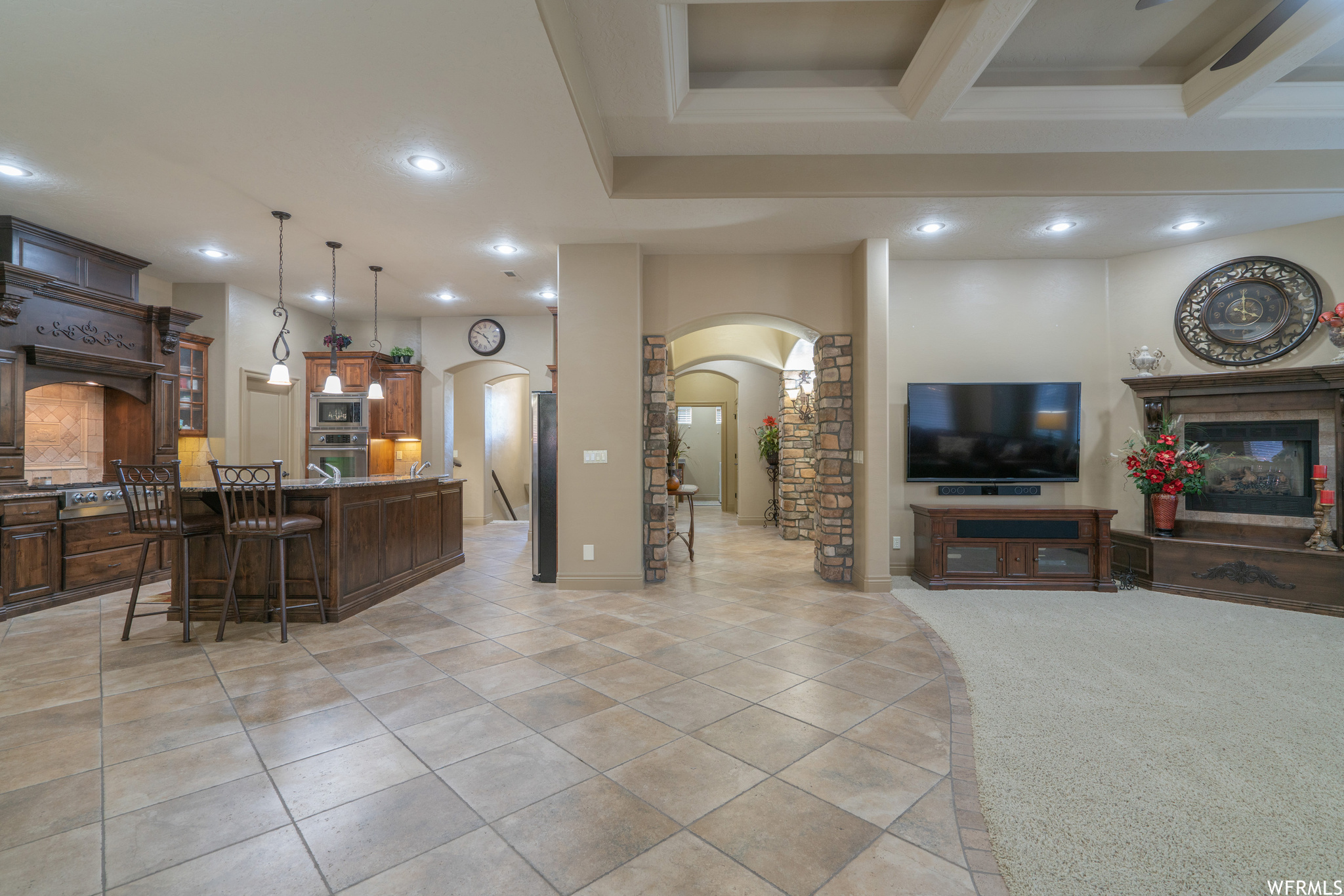 Kitchen featuring appliances with stainless steel finishes, a breakfast bar, decorative light fixtures, a center island with sink, and light carpet