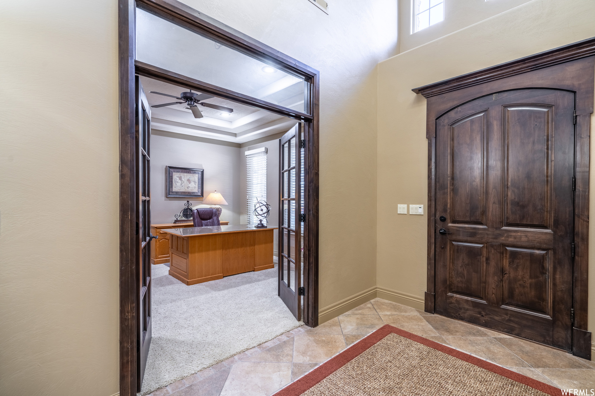 Carpeted entryway featuring ceiling fan and a tray ceiling