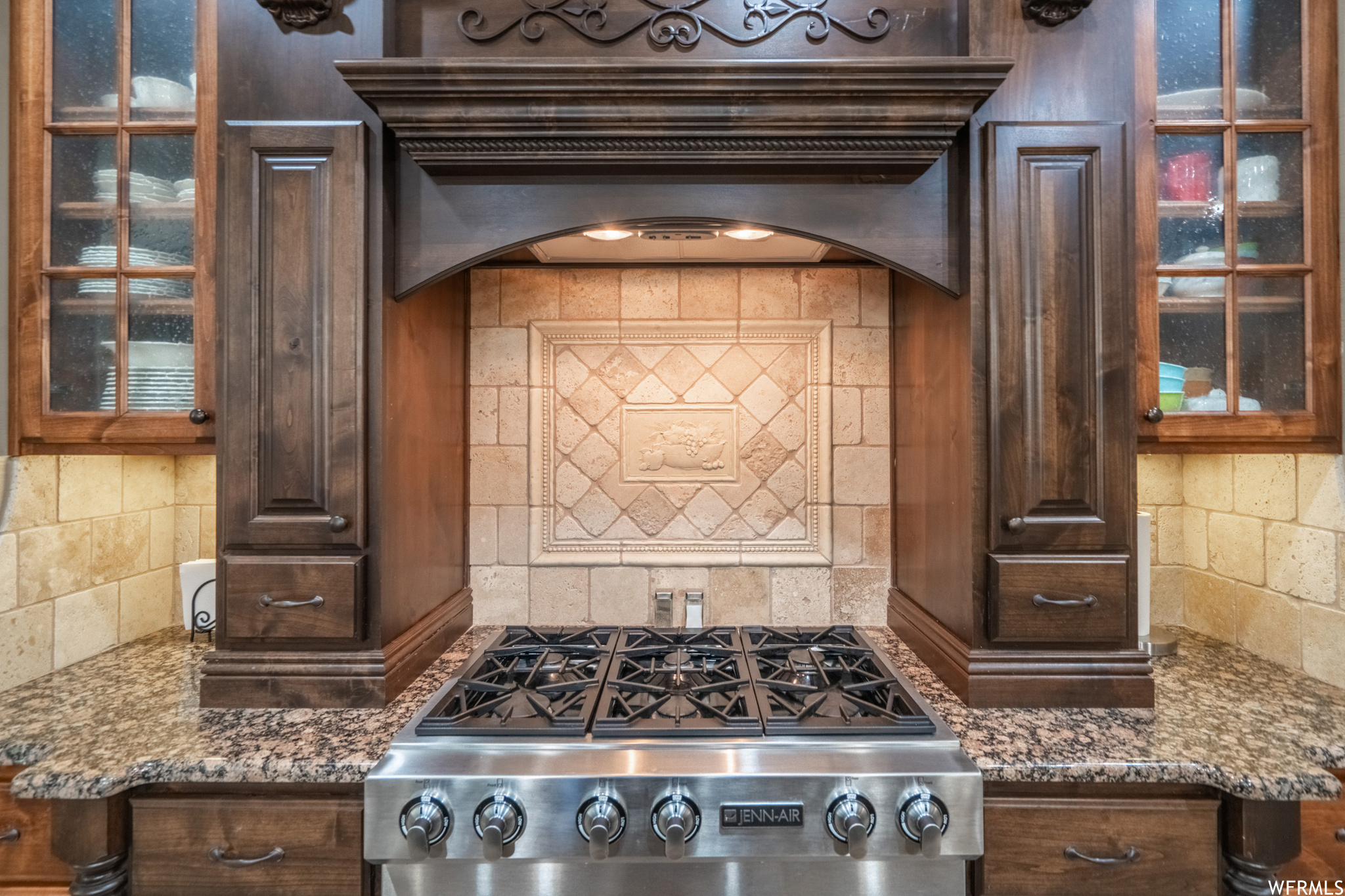 Kitchen with tasteful backsplash, dark brown cabinets, and dark stone counters