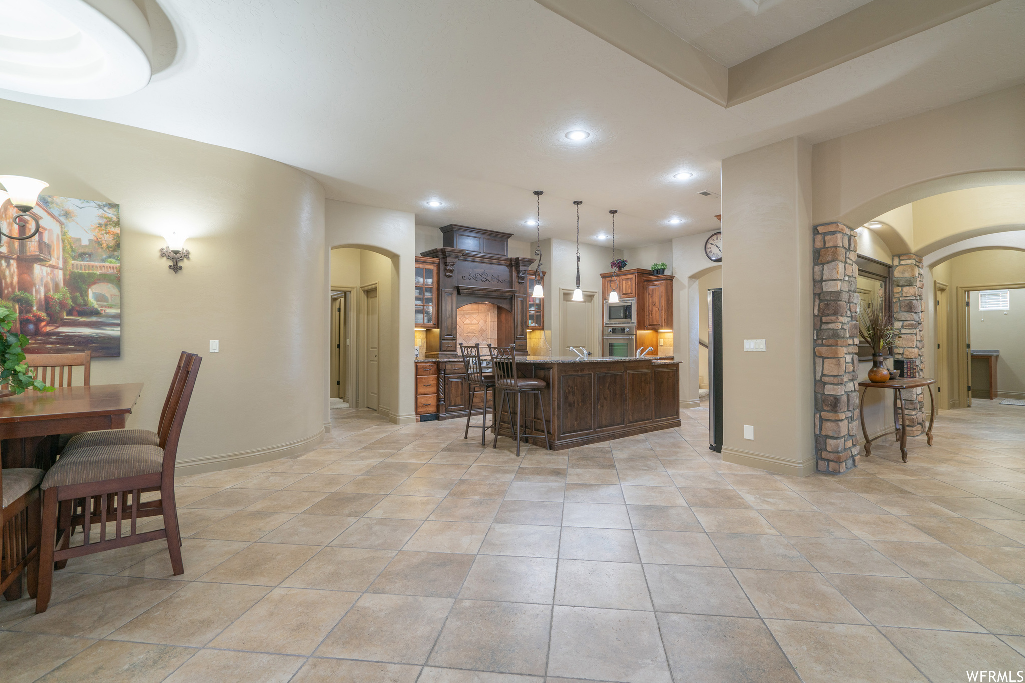 Kitchen with a center island, light tile floors, appliances with stainless steel finishes, a breakfast bar, and decorative light fixtures