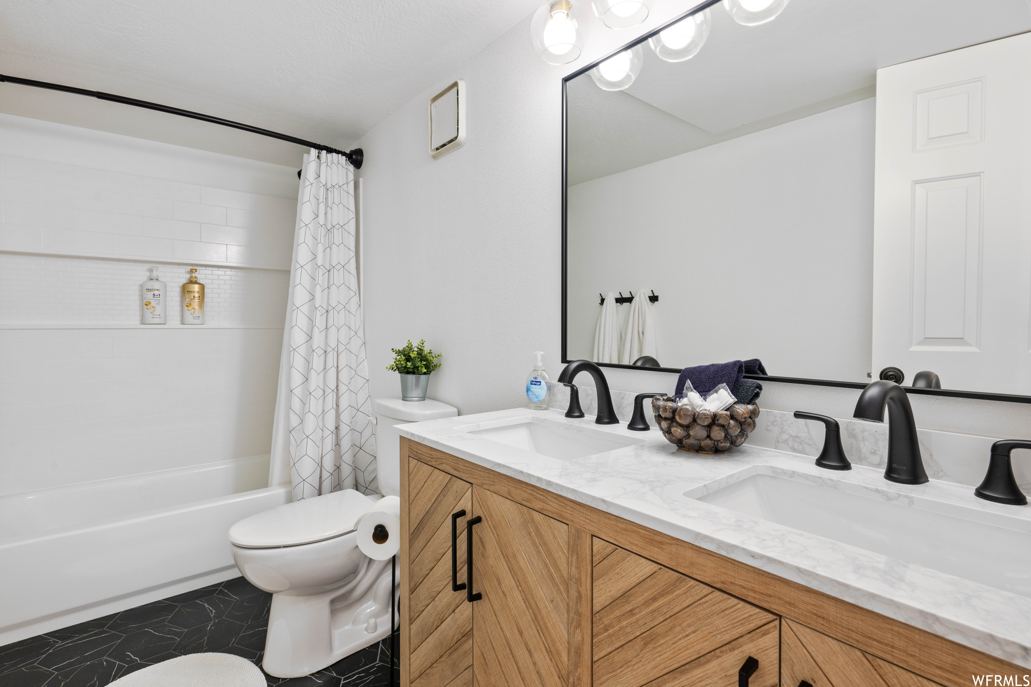 Full bathroom with toilet, tile floors, dual vanity, and shower / tub combo with curtain