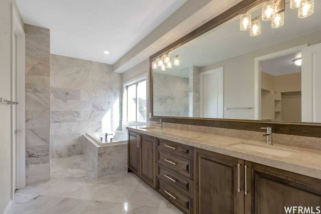 Bathroom with shower with separate bathtub, a notable chandelier, tile flooring, and dual bowl vanity