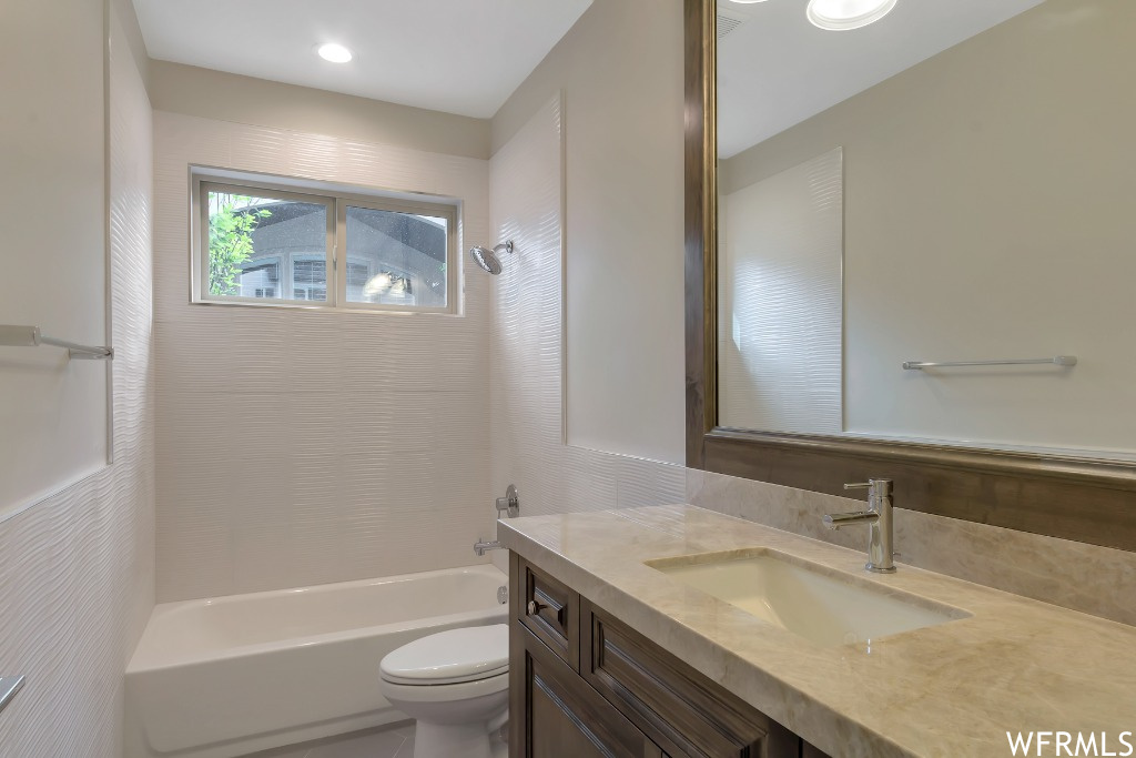 Full bathroom featuring toilet, large vanity, and bathing tub / shower combination