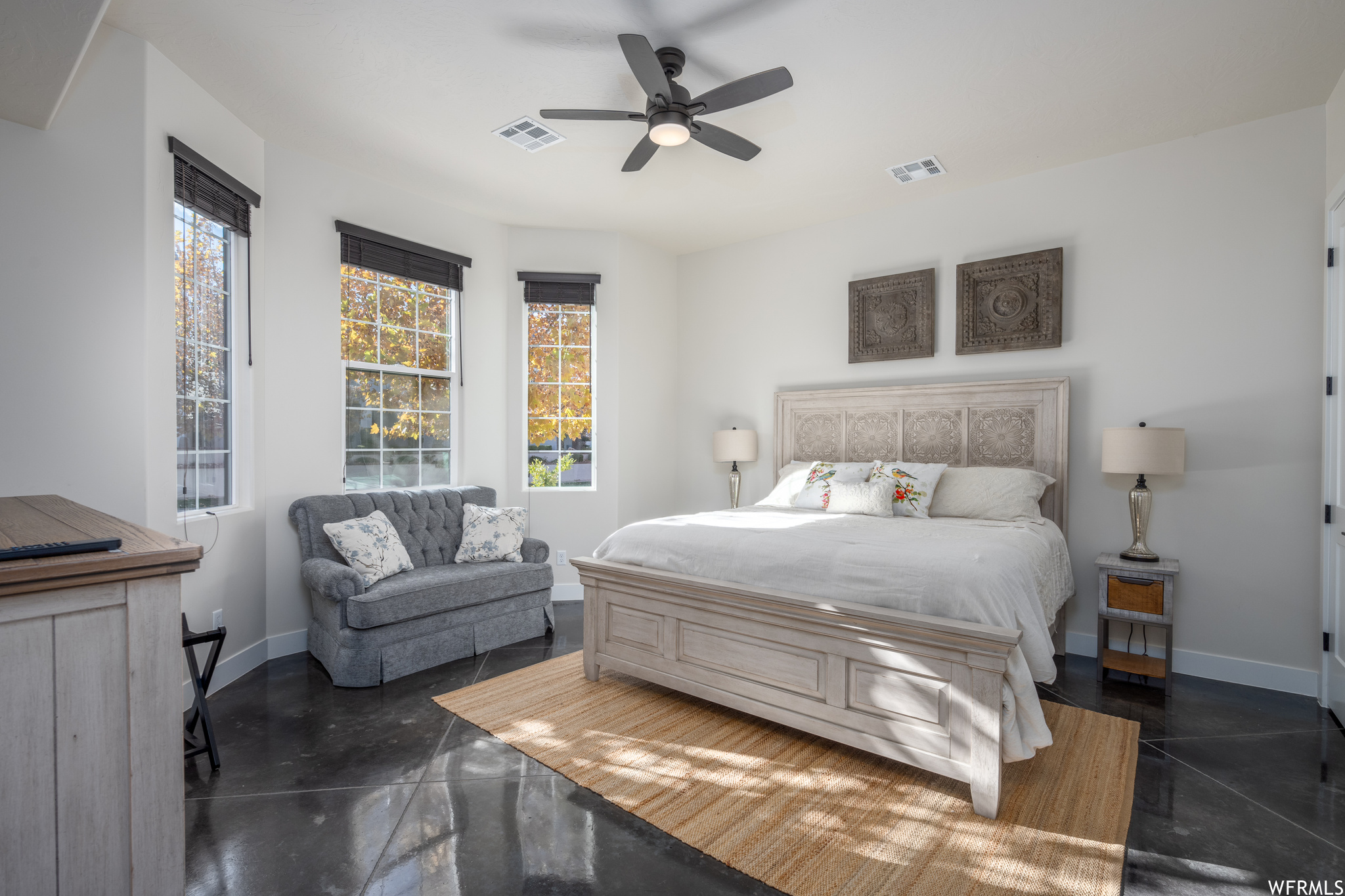 Tiled bedroom with ceiling fan and multiple windows
