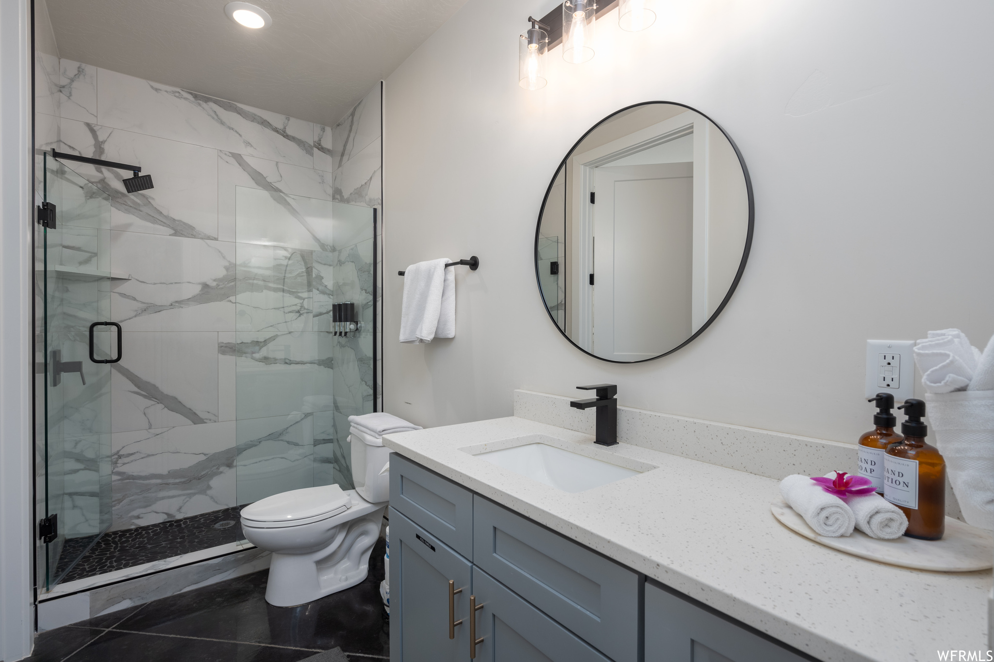 Bathroom featuring toilet, tile floors, a shower with shower door, and oversized vanity