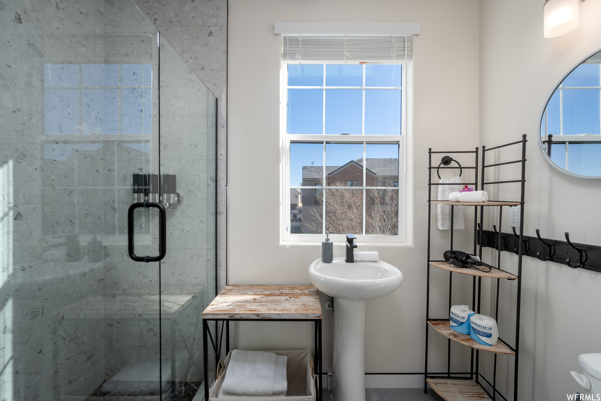 Bathroom with an enclosed shower, sink, and a wealth of natural light