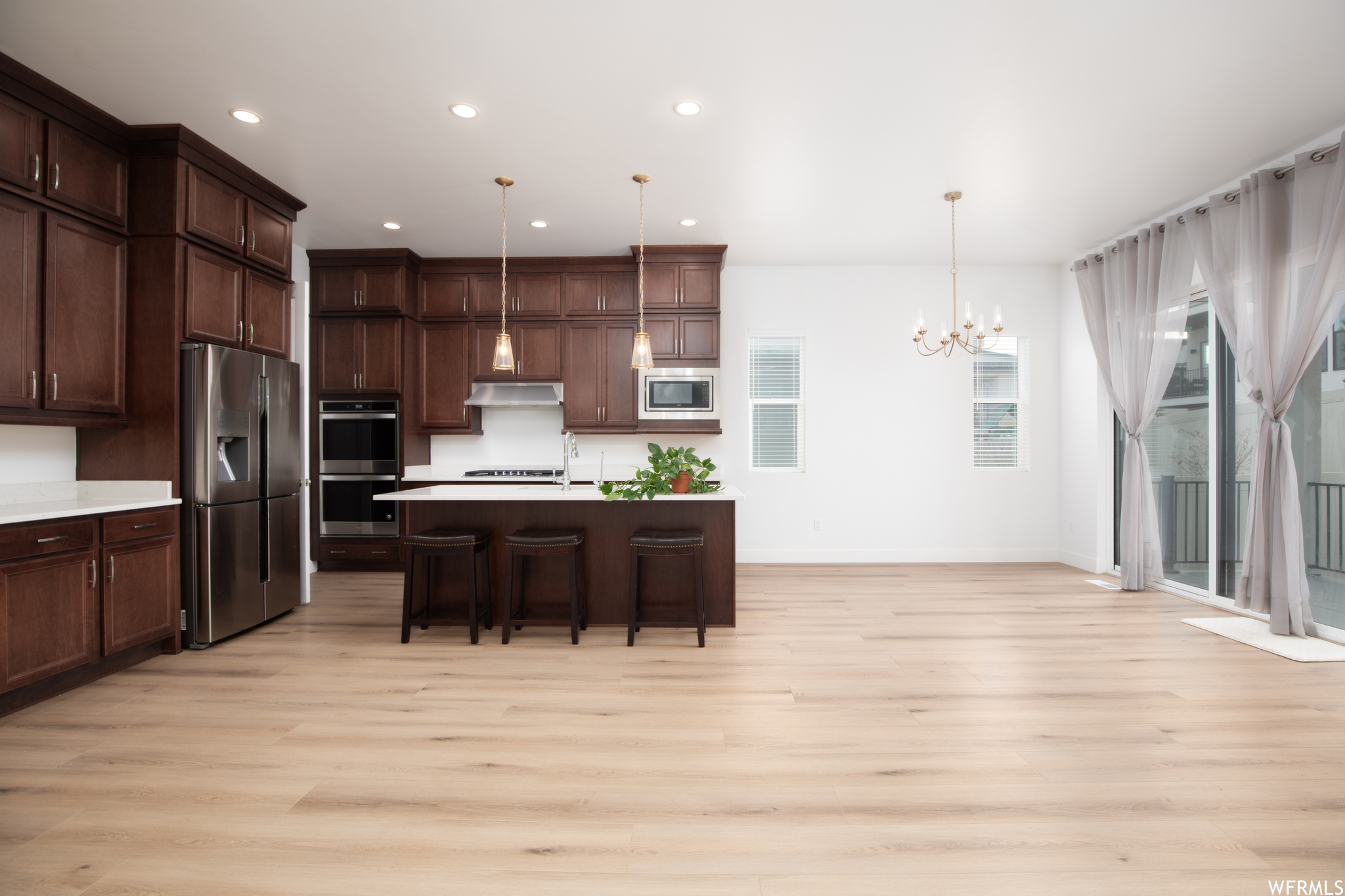 Kitchen with a wealth of natural light, light wood-type flooring, and appliances with stainless steel finishes