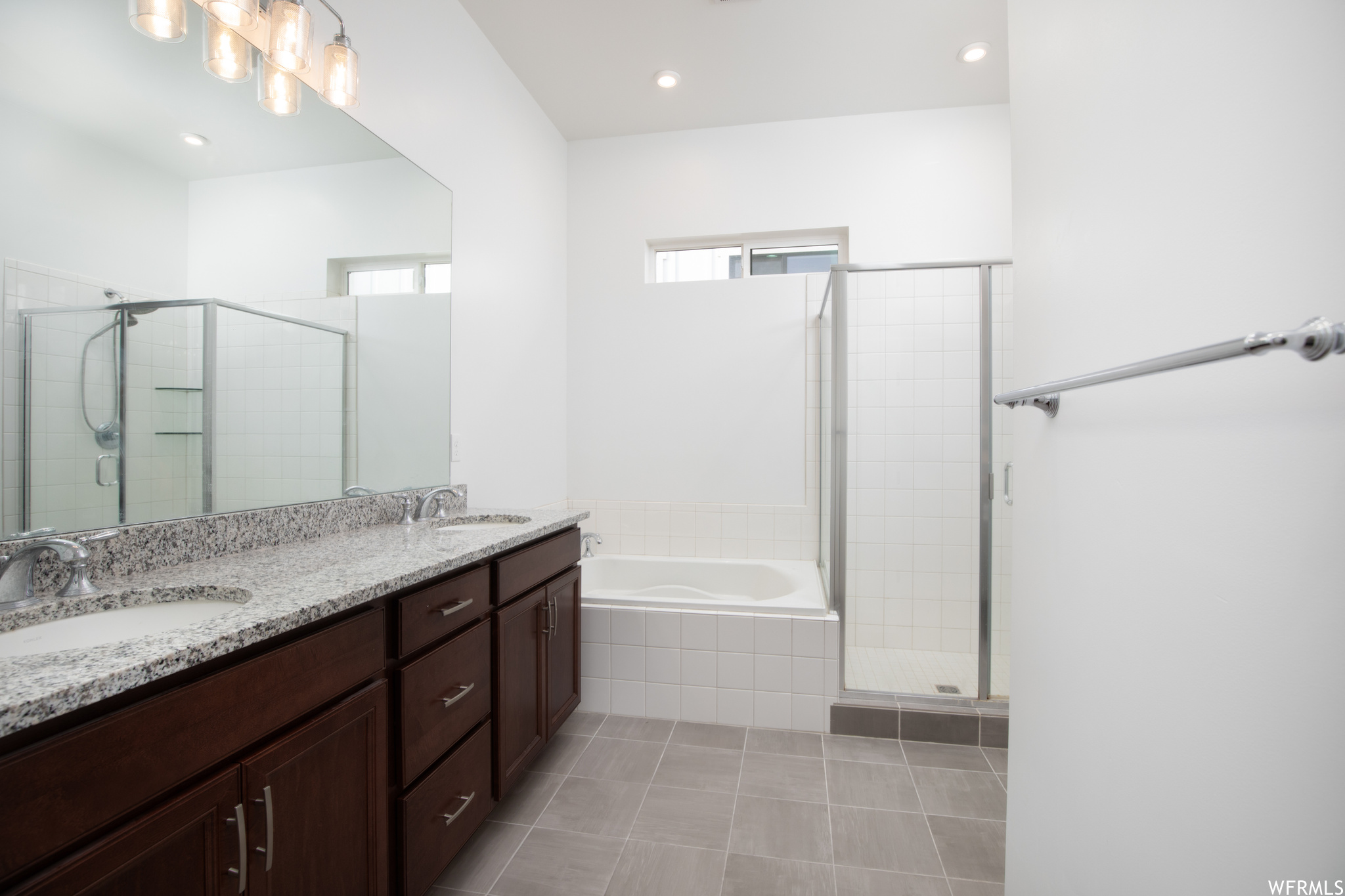 Bathroom featuring separate shower and tub, tile floors, oversized vanity, and dual sinks