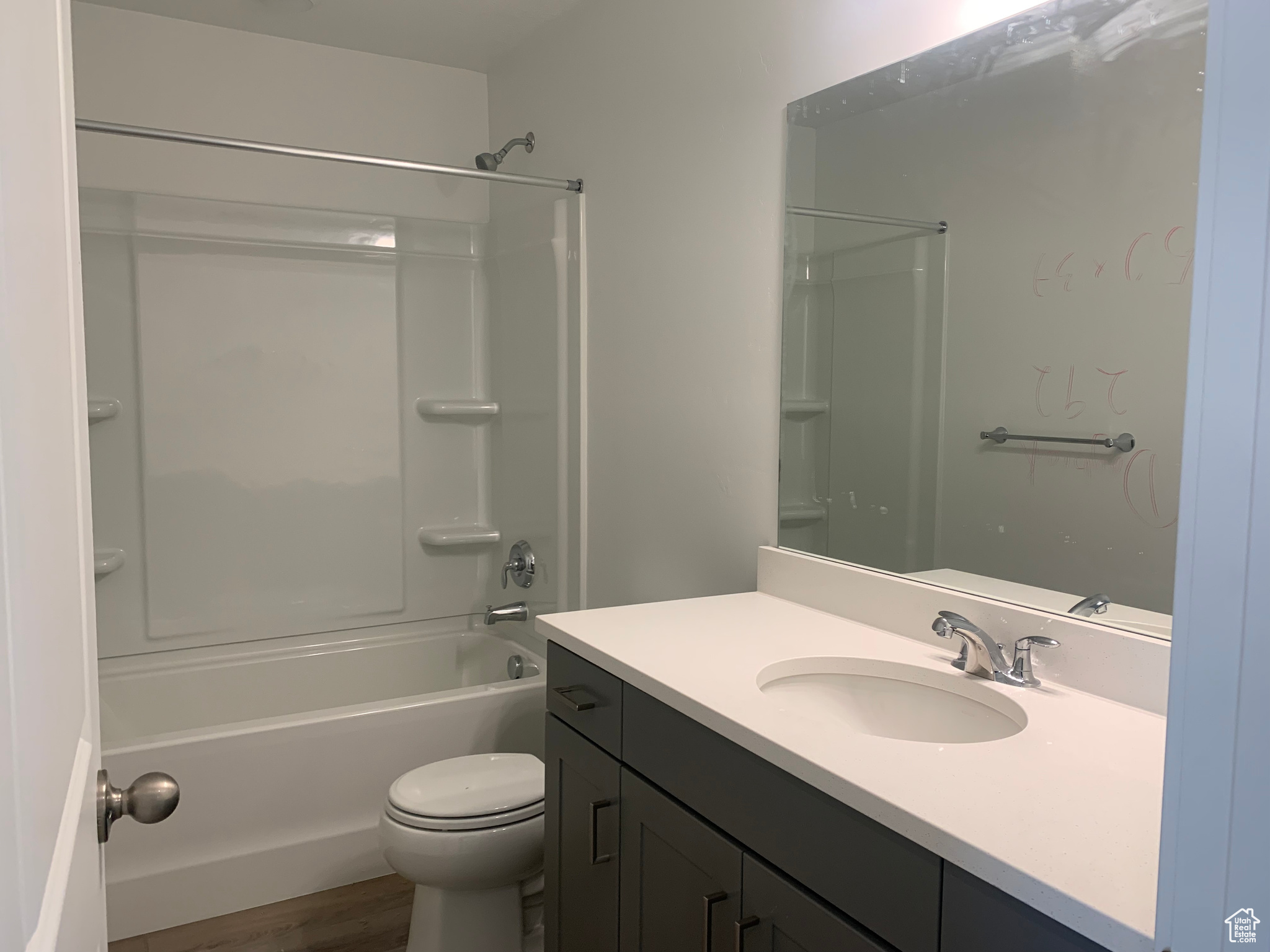 Full bathroom with shower / bathing tub combination, wood-type flooring, toilet, and vanity with extensive cabinet space