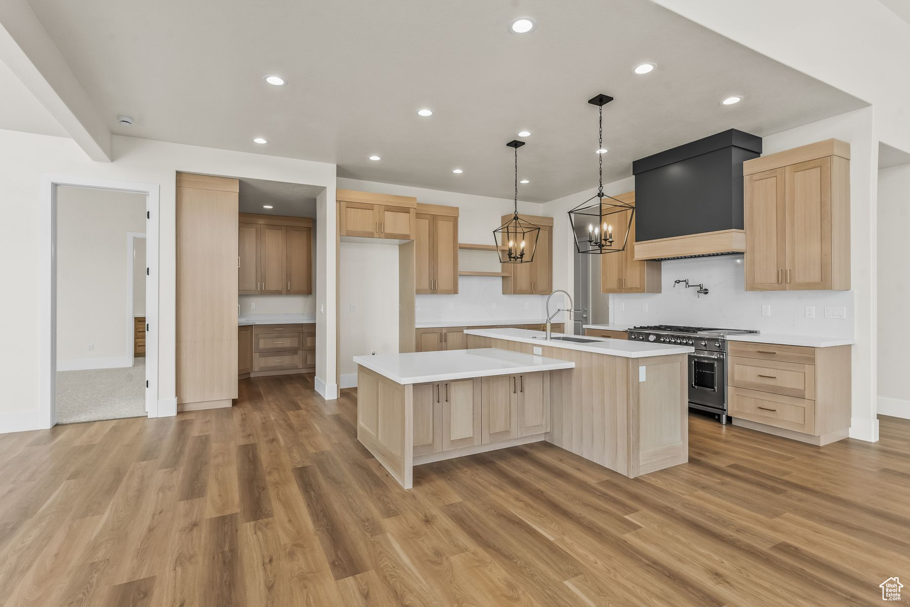 Kitchen featuring an island with sink, hardwood / wood-style flooring, custom exhaust hood, and range with two ovens