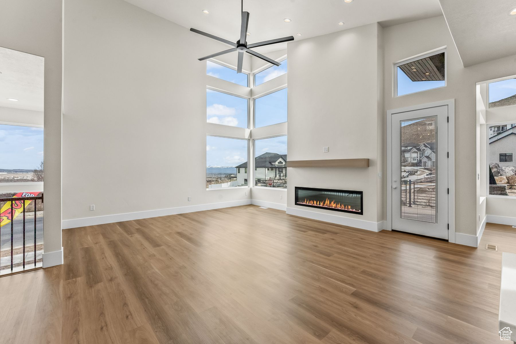 Unfurnished living room featuring wood-type flooring, a towering ceiling, and plenty of natural light