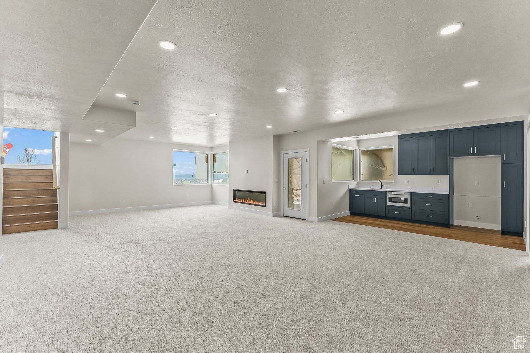 Unfurnished living room with light colored carpet and sink