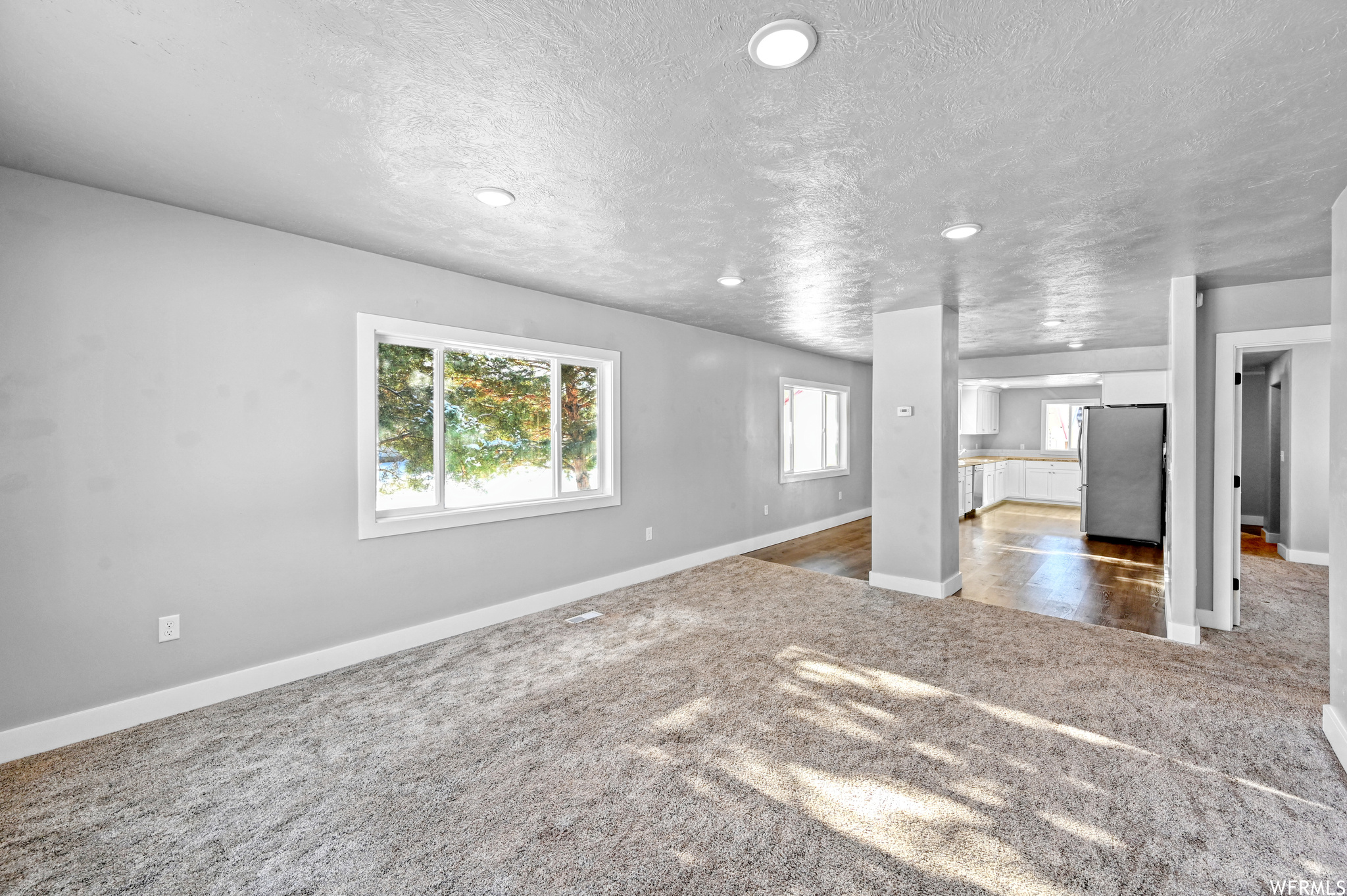Unfurnished living room with carpet and a textured ceiling