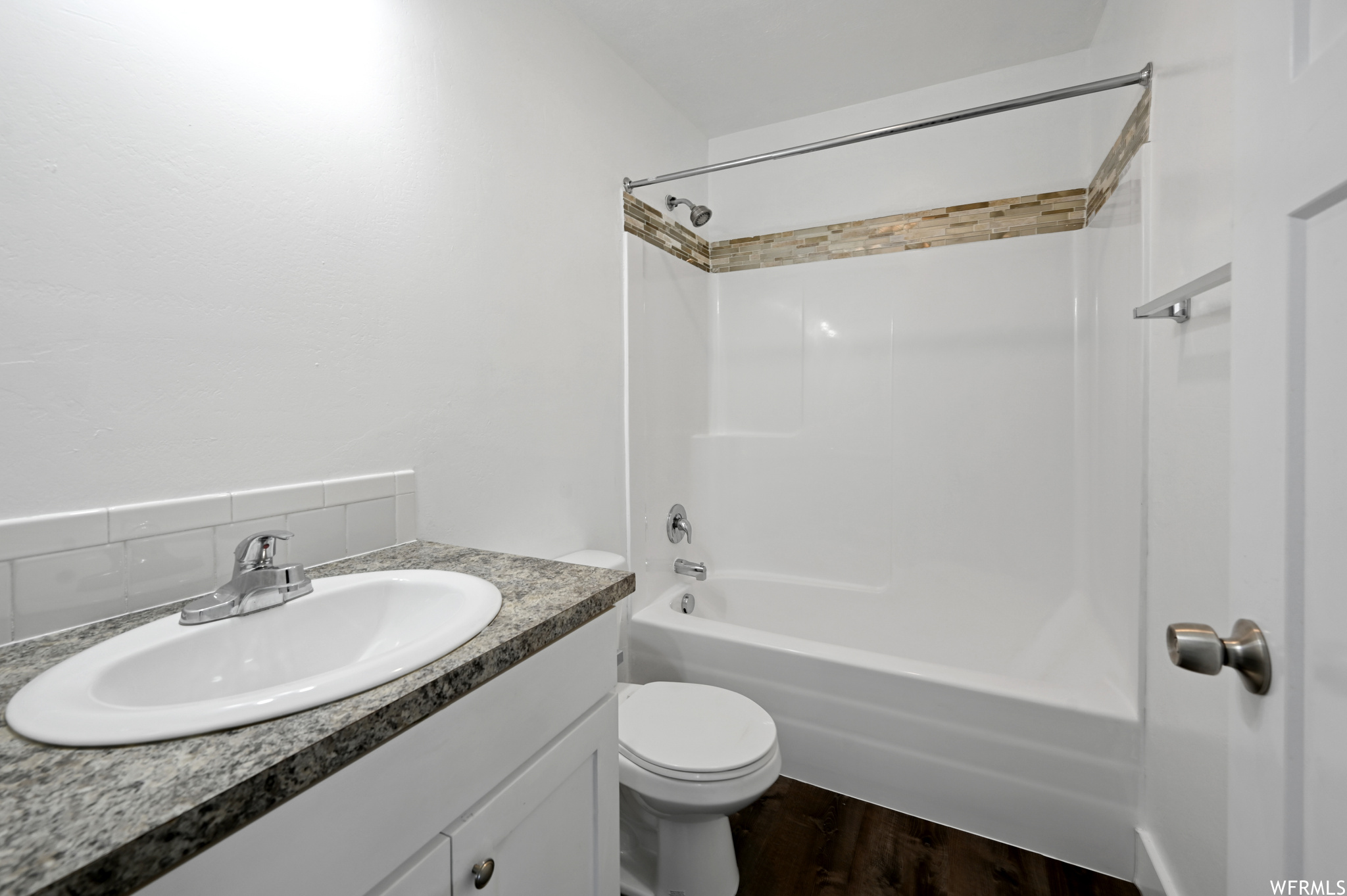Full bathroom featuring bathtub / shower combination, toilet, vanity, and wood-type flooring