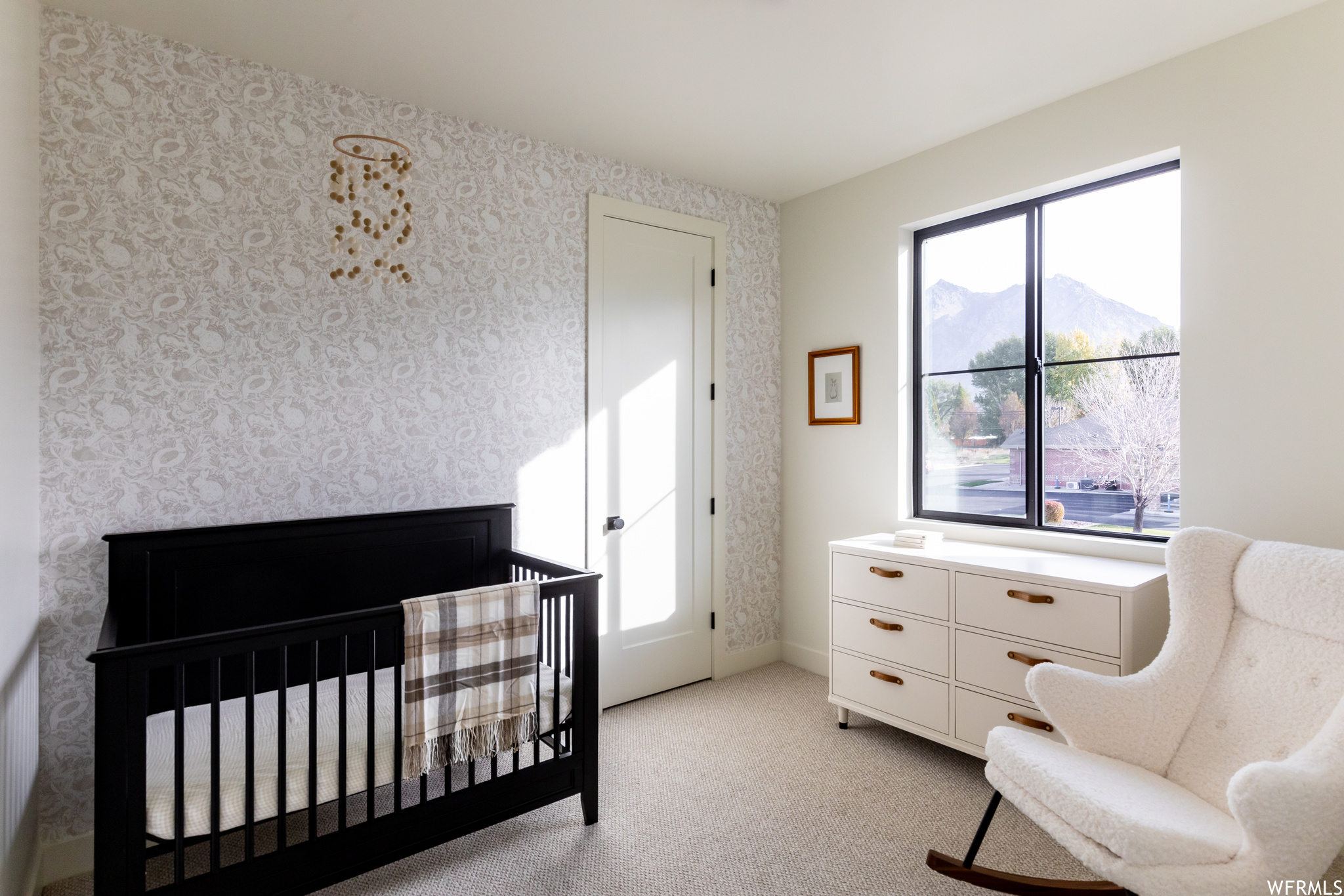 Carpeted bedroom with multiple windows, a crib, and a mountain view