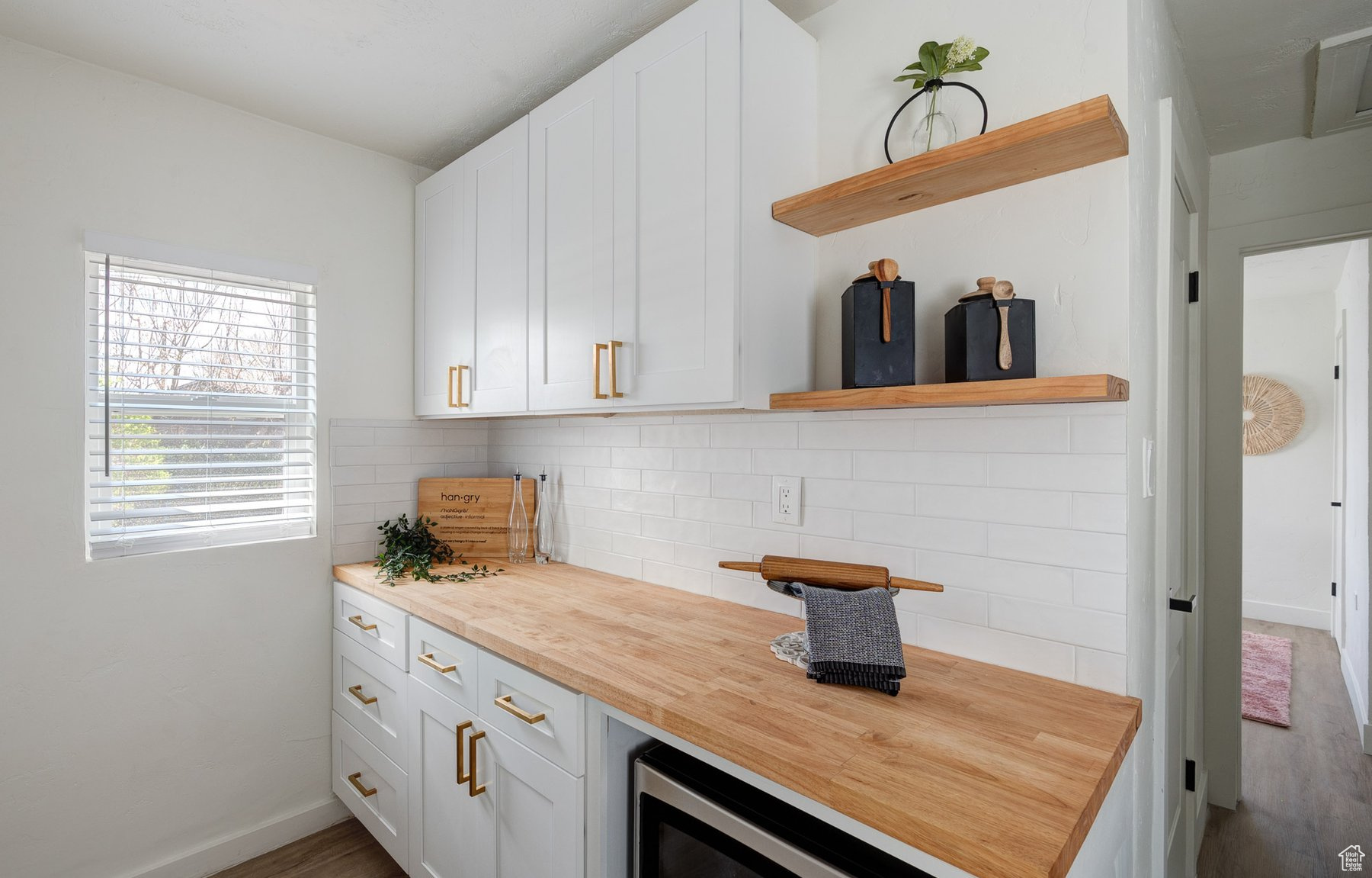 Nook pantry area with floating wood shelving, white backsplash and brushed gold finishes