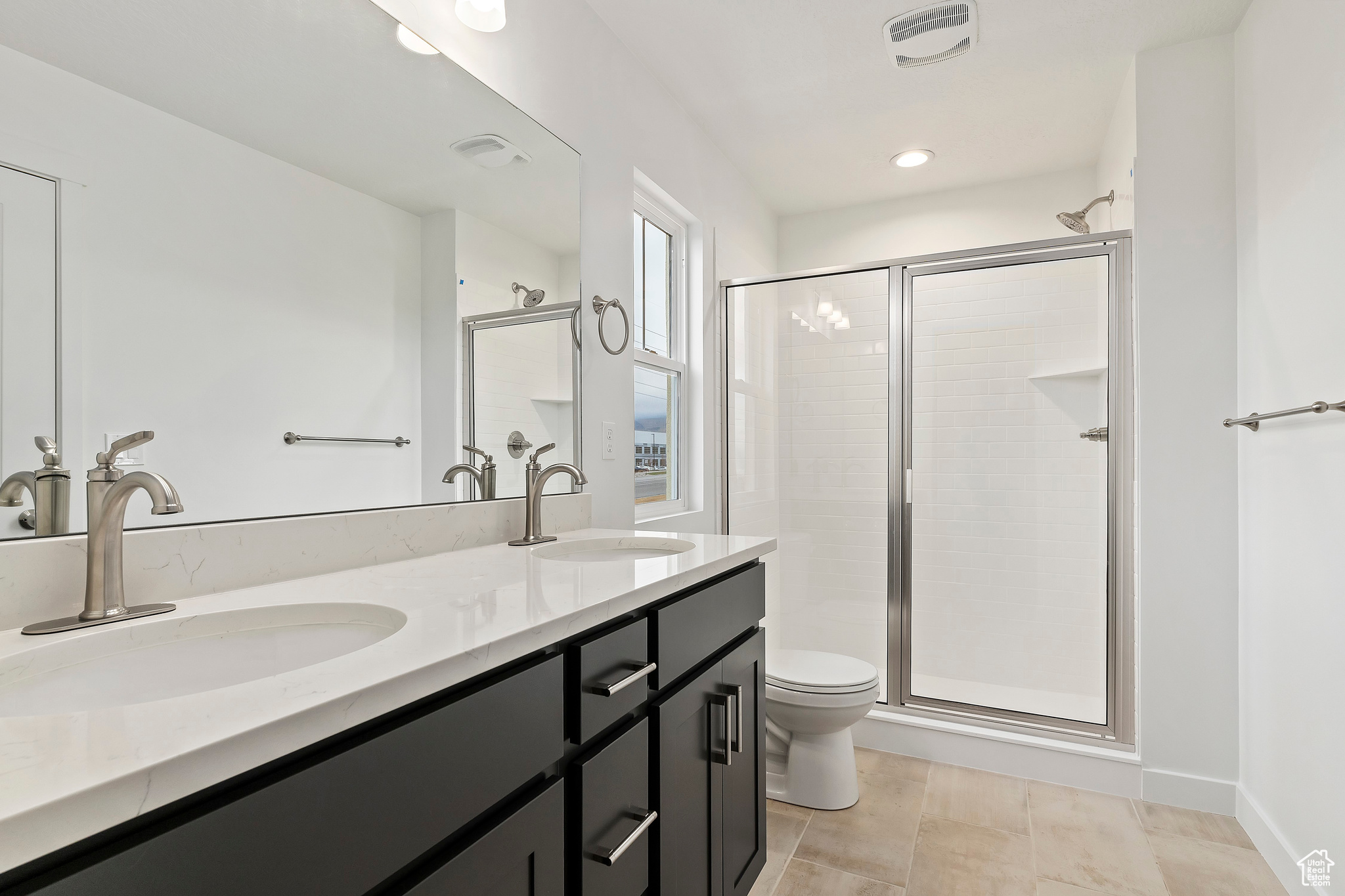 Bathroom with tile patterned flooring, a shower with shower door, vanity, and toilet