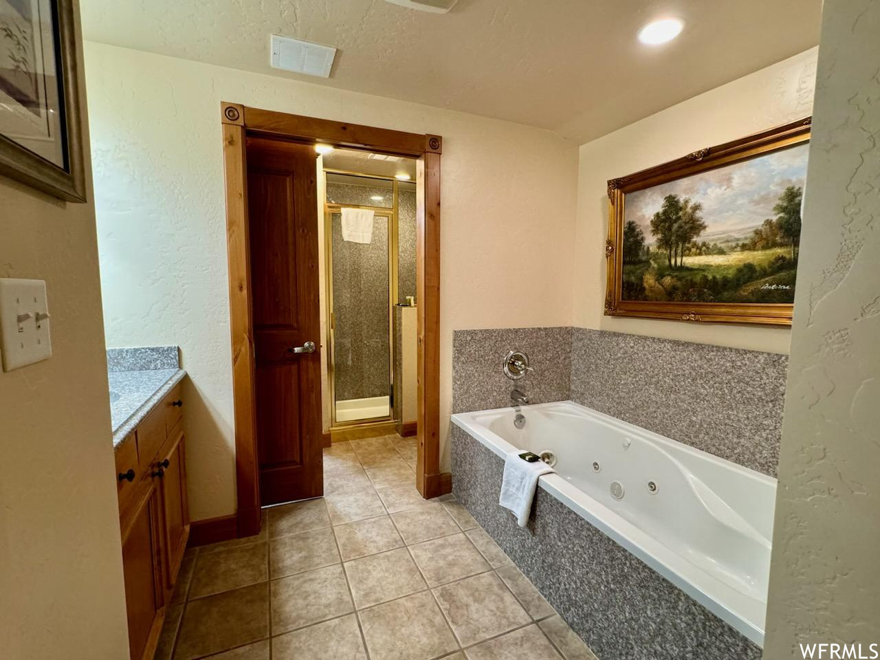 Bathroom featuring separate shower and tub, tile floors, a textured ceiling, and vanity