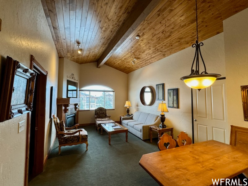 Carpeted living room featuring wooden ceiling and lofted ceiling with beams