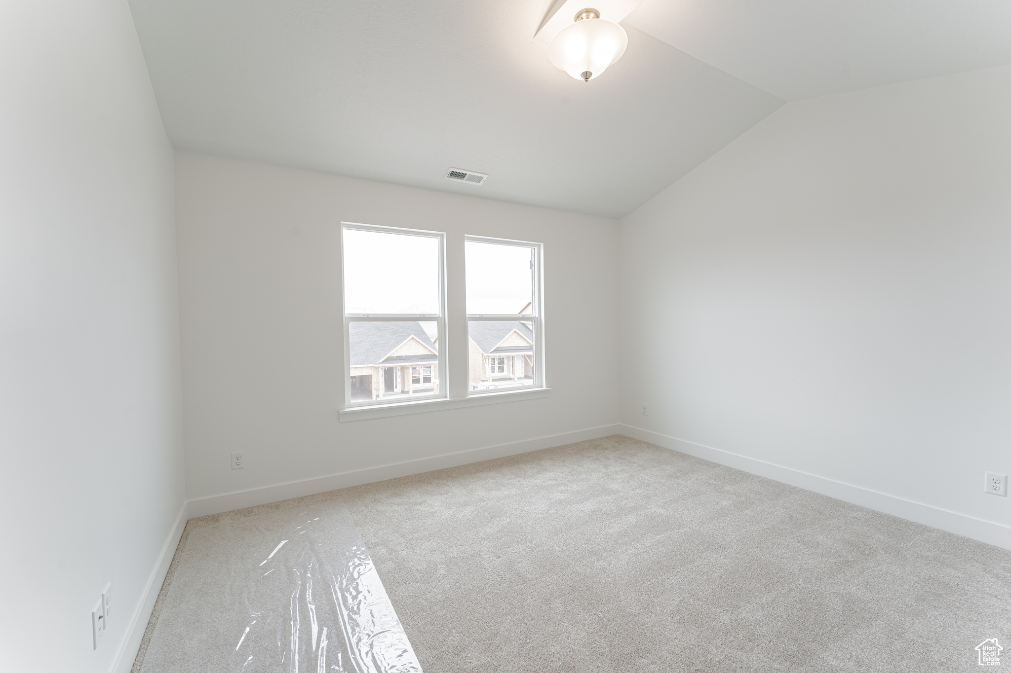Empty room with light carpet and vaulted ceiling