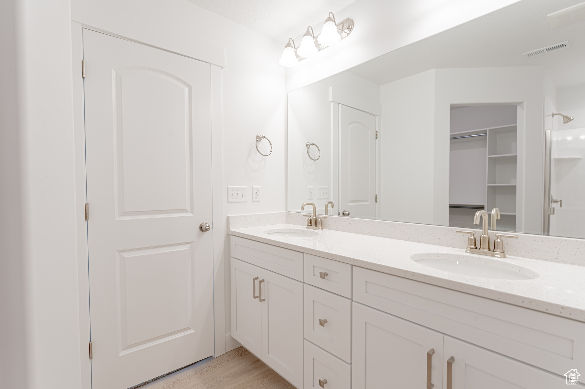Bathroom with dual sinks, vanity with extensive cabinet space, and hardwood / wood-style flooring
