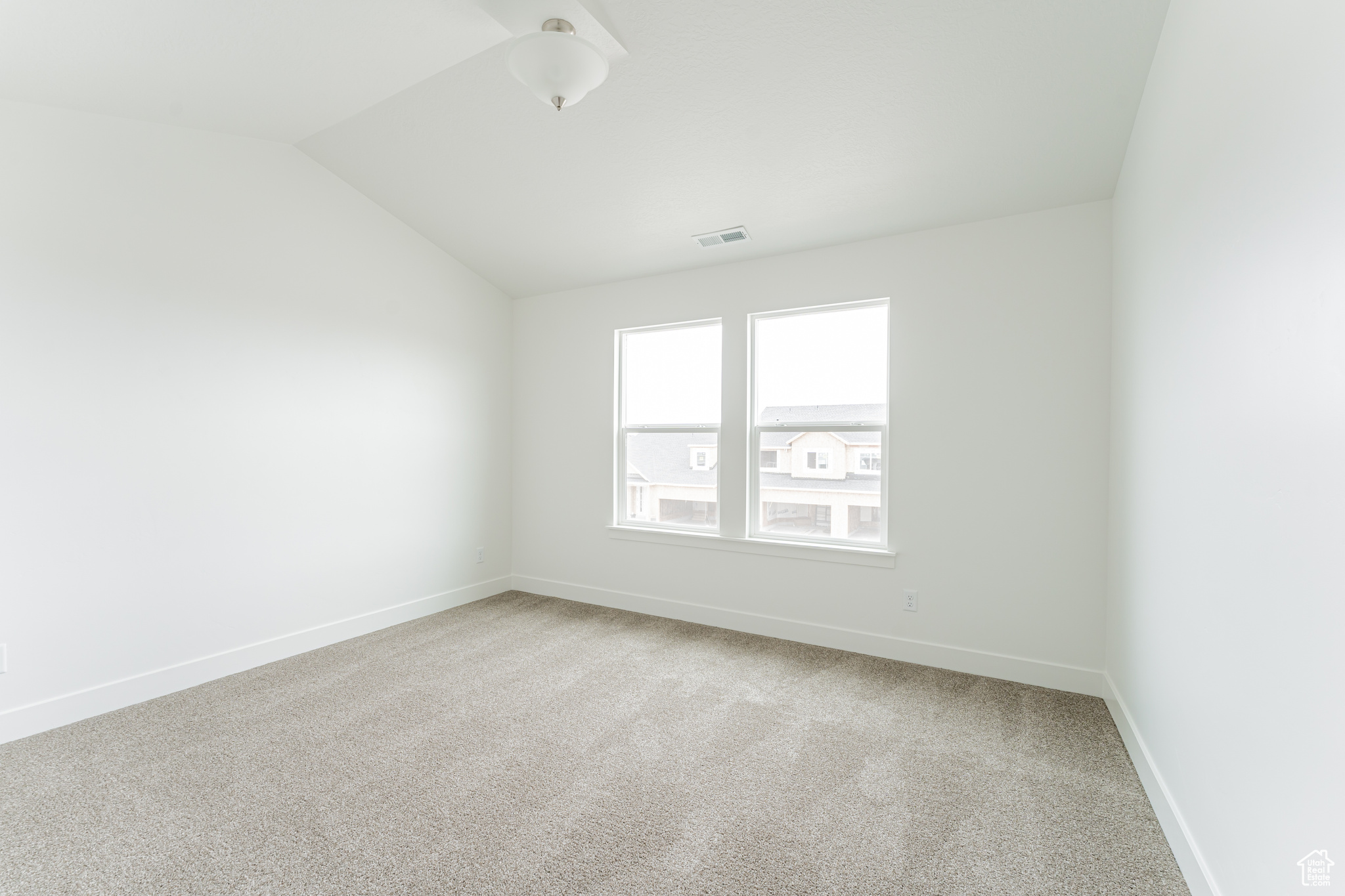 Carpeted empty room with lofted ceiling