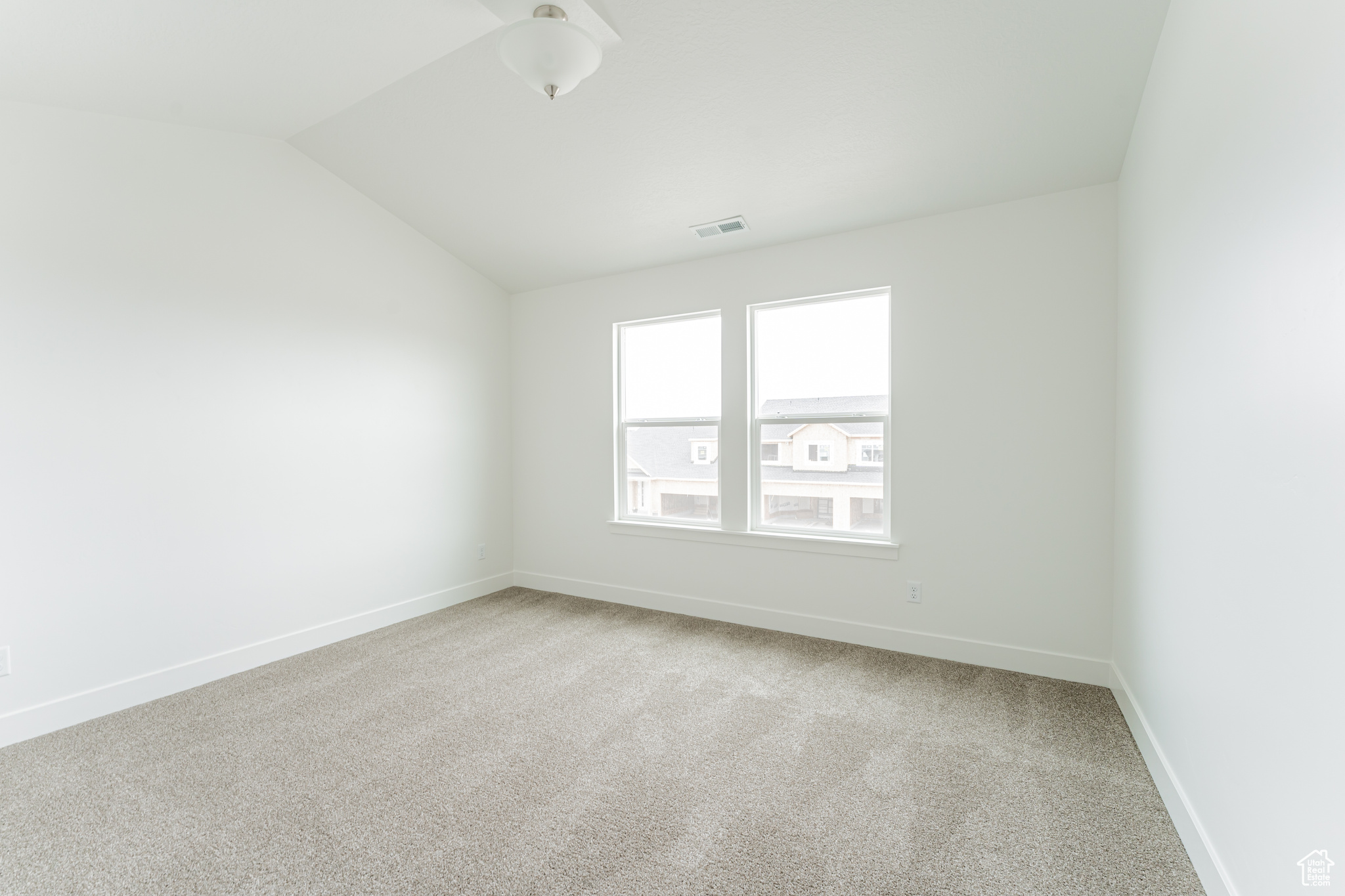 Spare room with vaulted ceiling and light colored carpet