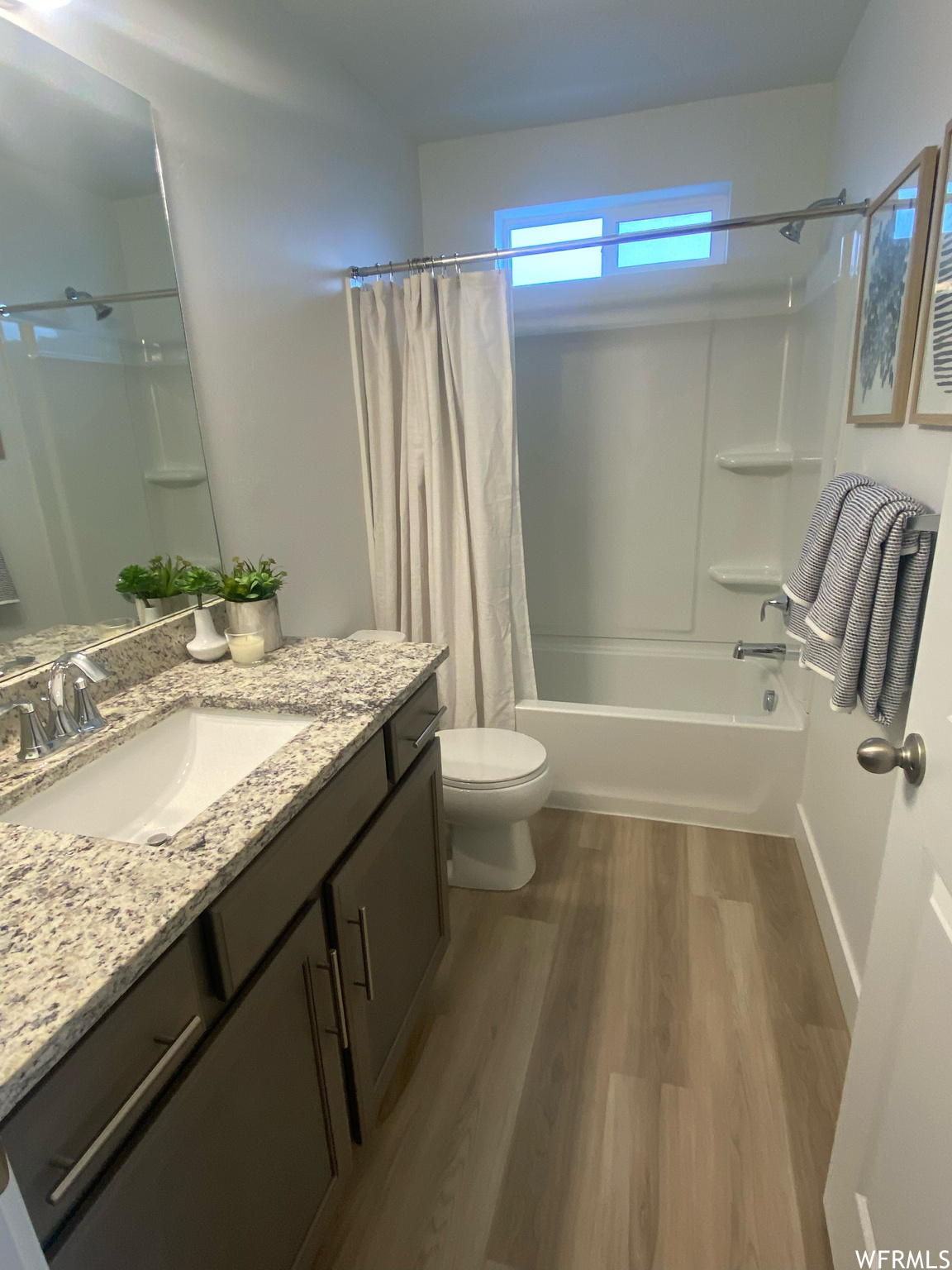 Full bathroom featuring oversized vanity, toilet, shower / bath combo, and hardwood / wood-style flooring