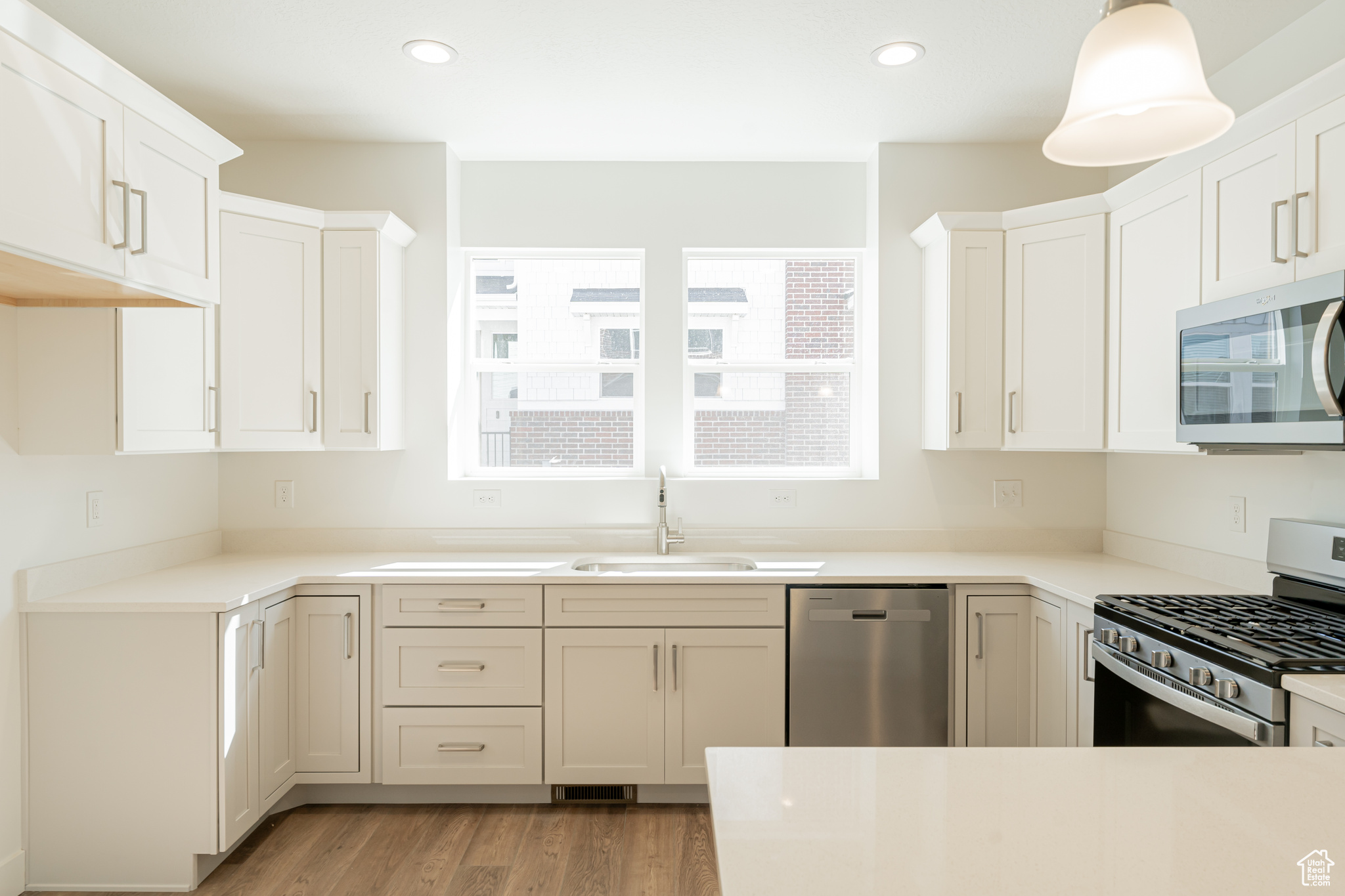 Kitchen featuring white cabinets, appliances with stainless steel finishes, light hardwood / wood-style flooring, and a healthy amount of sunlight