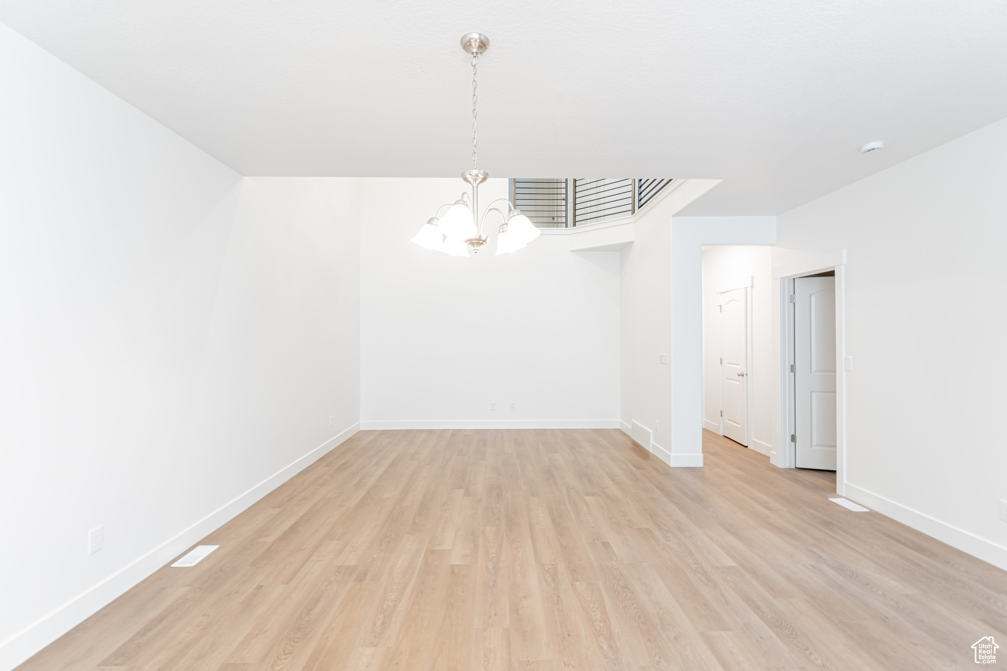 Unfurnished room featuring a notable chandelier and light hardwood / wood-style flooring