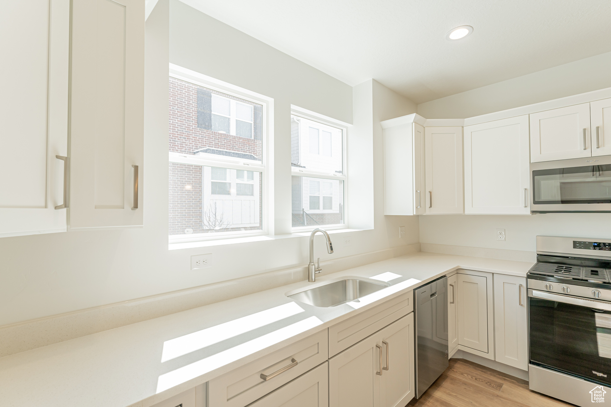 Kitchen featuring a wealth of natural light, light hardwood / wood-style flooring, stainless steel appliances, and sink