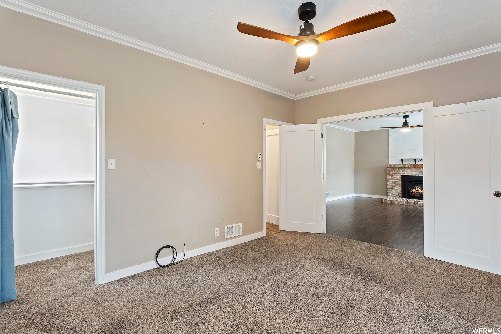 Unfurnished room featuring ornamental molding, ceiling fan, a fireplace, and carpet flooring