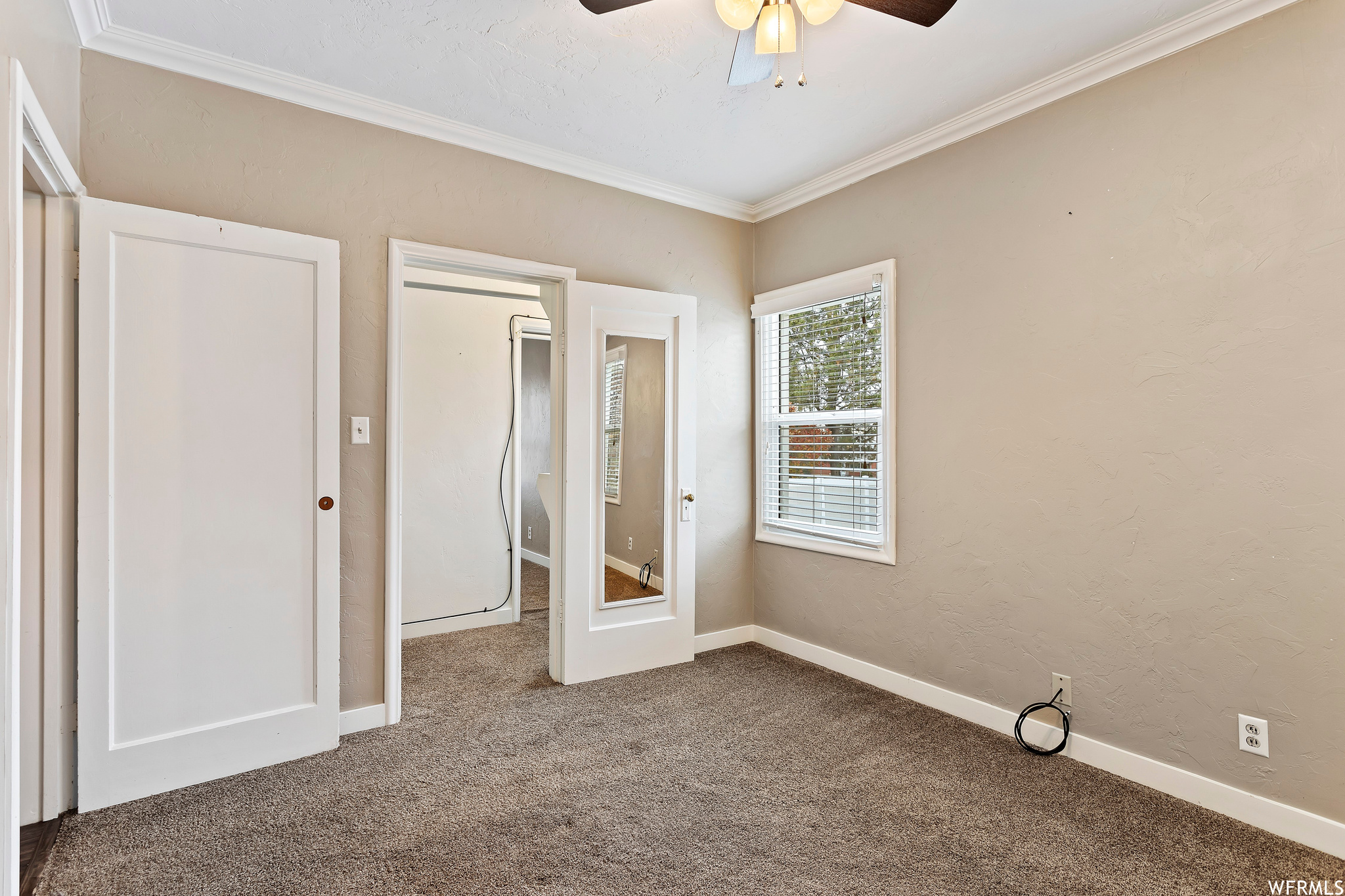 Unfurnished bedroom with ceiling fan, carpet, and crown molding