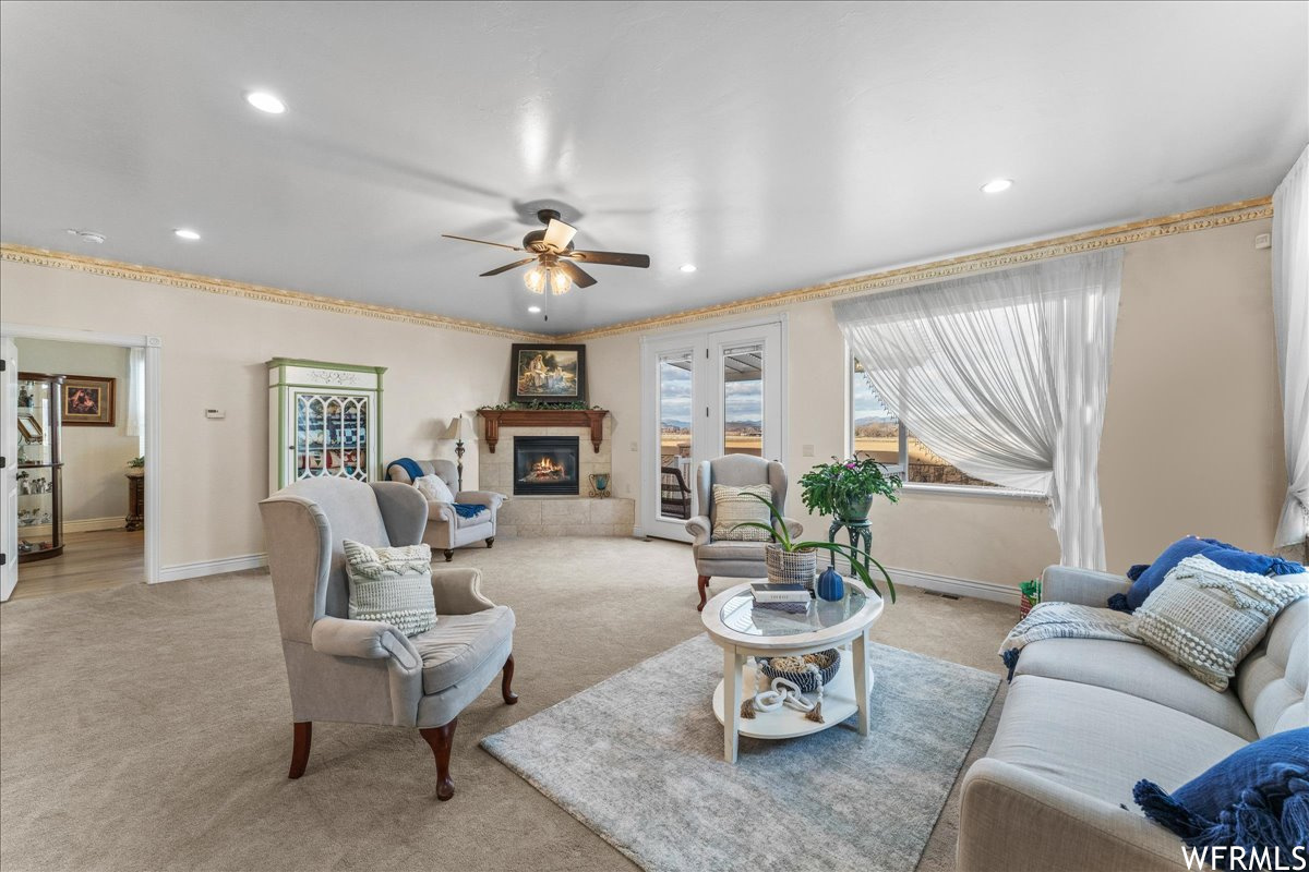 Living room with light carpet, a tile fireplace, and ceiling fan